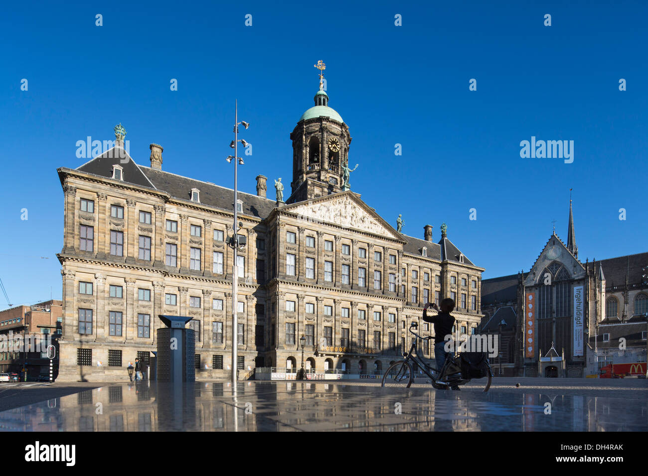 Niederlande, Amsterdam, königlicher Palast auf dem Dam. Frau mit dem Fahrrad nimmt Bild Stockfoto