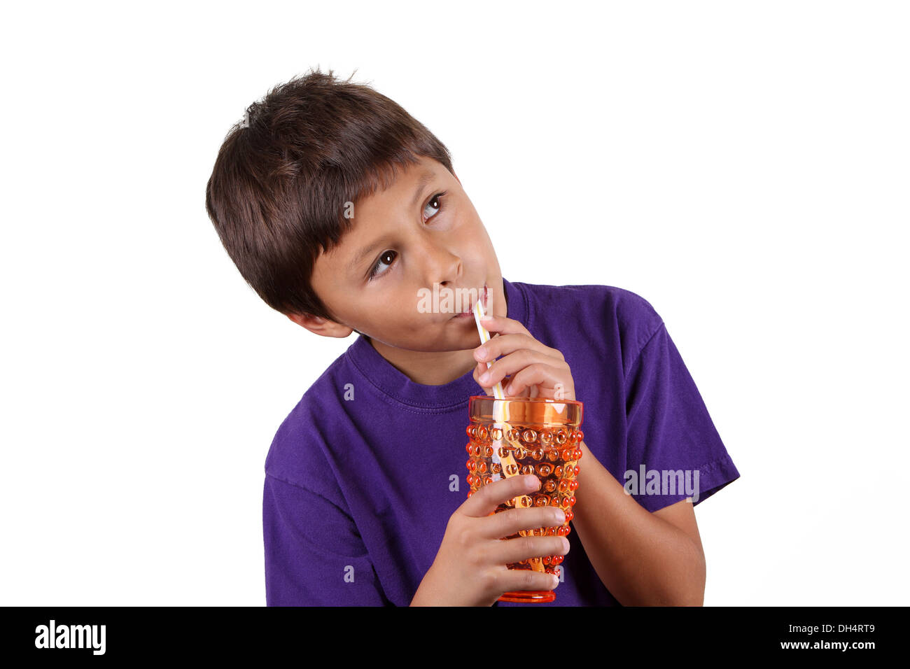 Kleiner Junge trinken aus orange Glas auf weißem Hintergrund Stockfoto