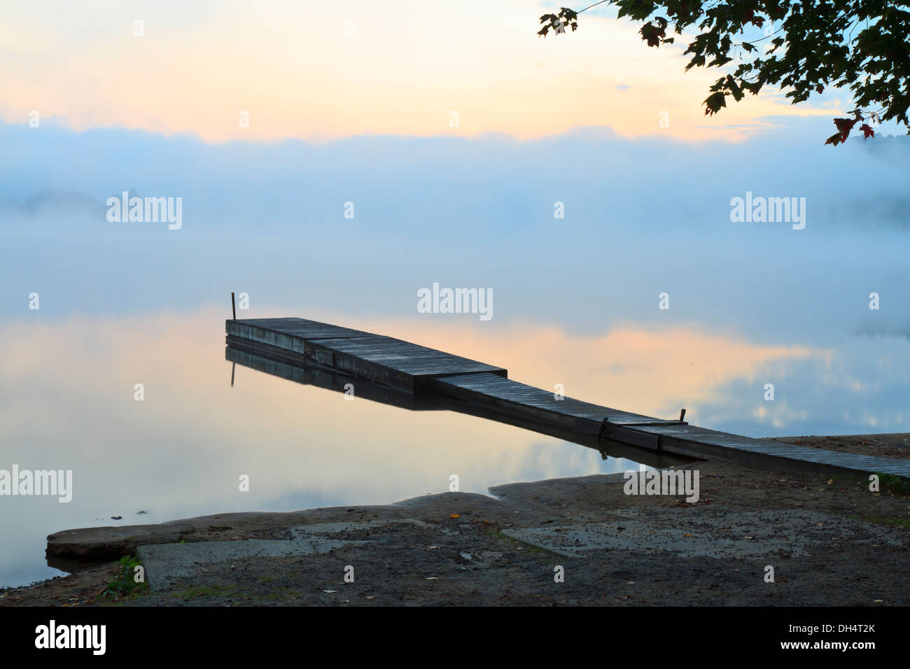 Nebligen Sonnenaufgang auf einem ruhigen Dock auf Achtel-See in den Adirondacks-Bergen von New York Stockfoto