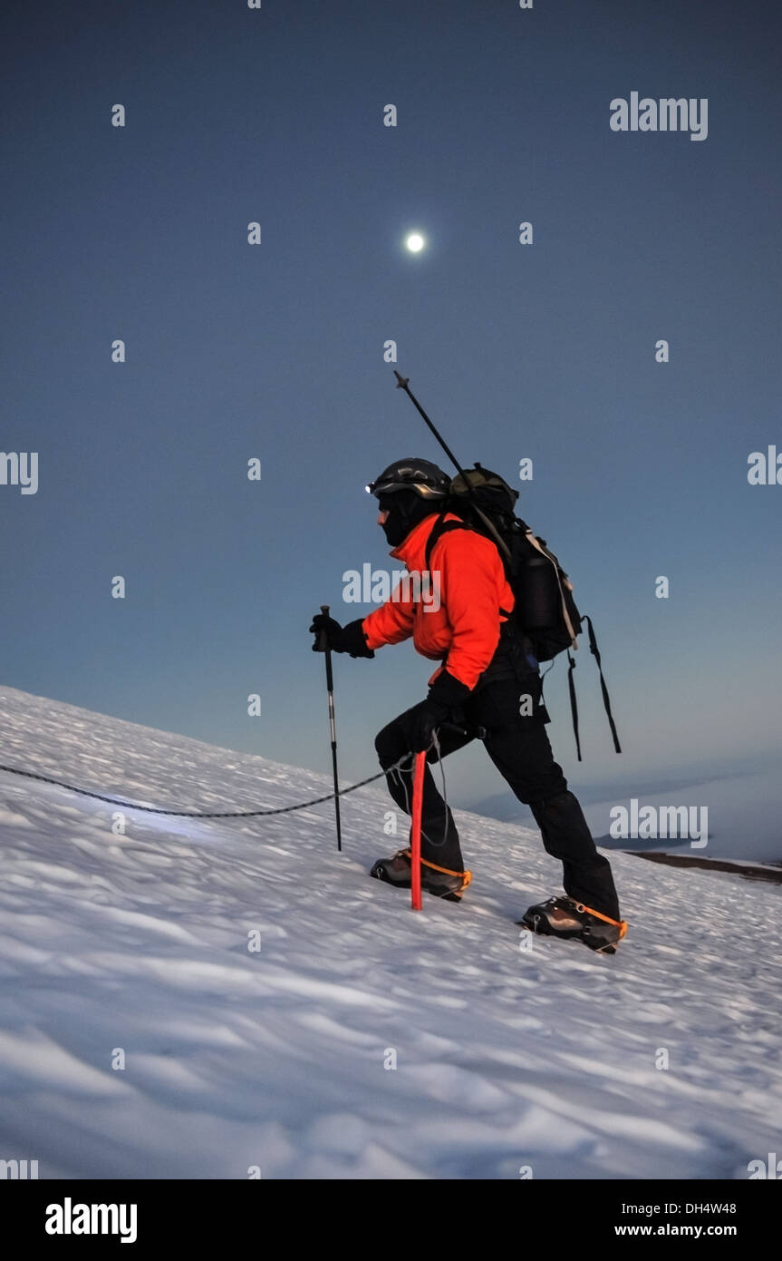 Eine alpine Bergsteiger besteigt einen Gletscher bei Vollmond. Stockfoto