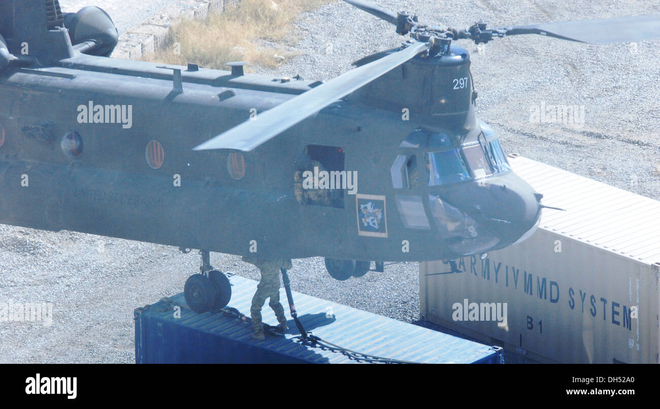 Ein Crewchef leitet die Piloten eine 10. Combat Aviation Brigade CH-47 Chinook Hubschrauber wie es über einem Versandbehälter schwebt, Schlinge unter den Bauch des Flugzeugs, 26. Okt. um vorwärts operative Basis Airborne, Afghanistan geladen zu sein. Die Flug-cr Stockfoto