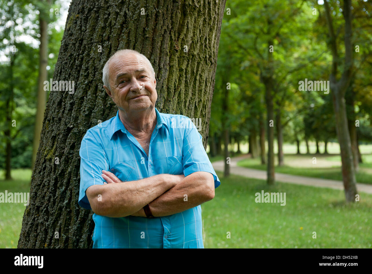 Älterer Mann lehnte sich gegen einen Baum, in einer guten Stimmung Stockfoto