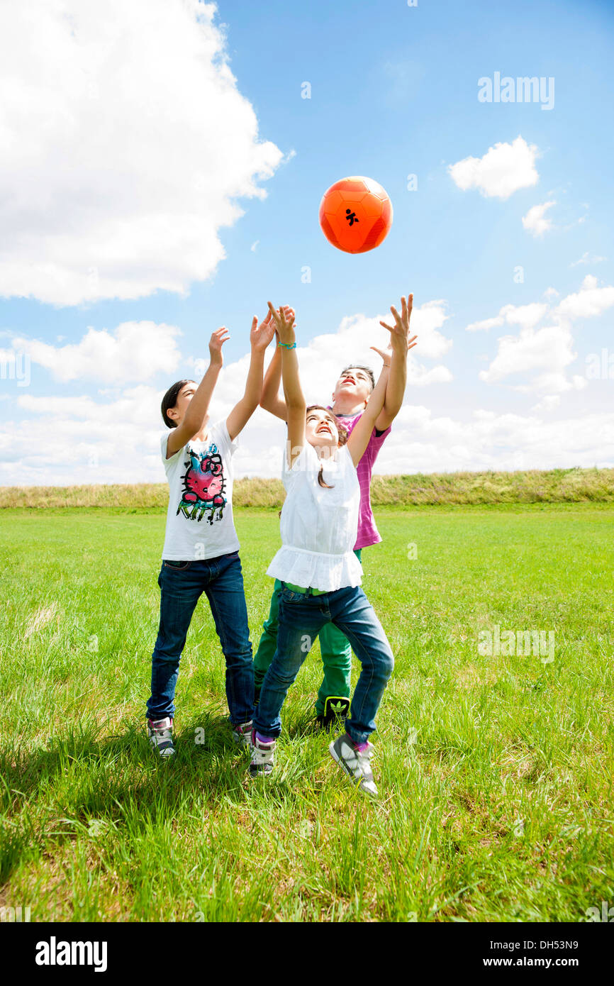 Drei Kinder Ballspielen auf der Wiese Stockfoto