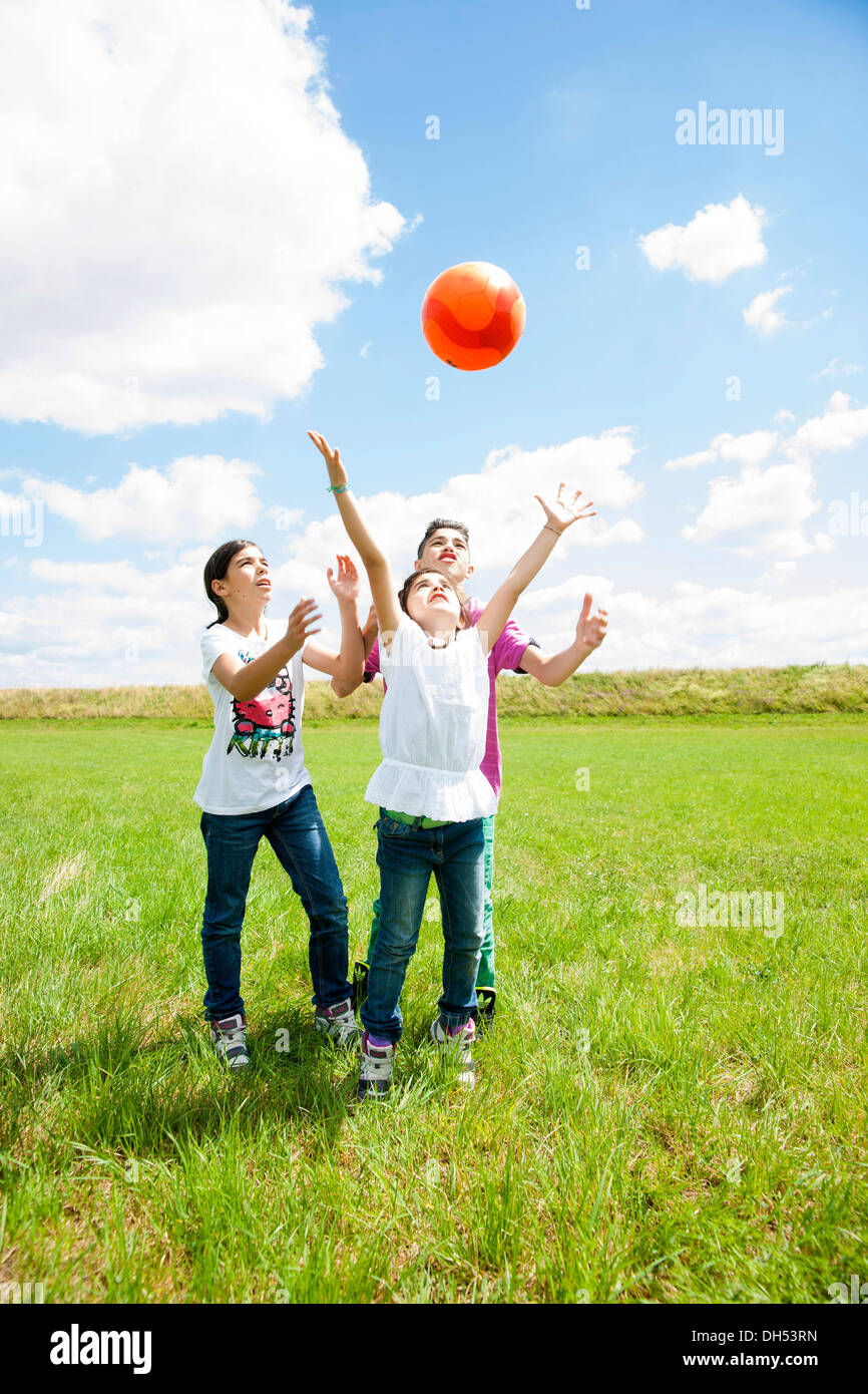 Drei Kinder Ballspielen auf der Wiese Stockfoto