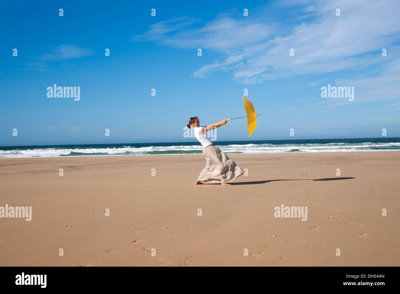 Frau zu Fuß mit einem Regenschirm auf einem windigen Strand Stockfoto
