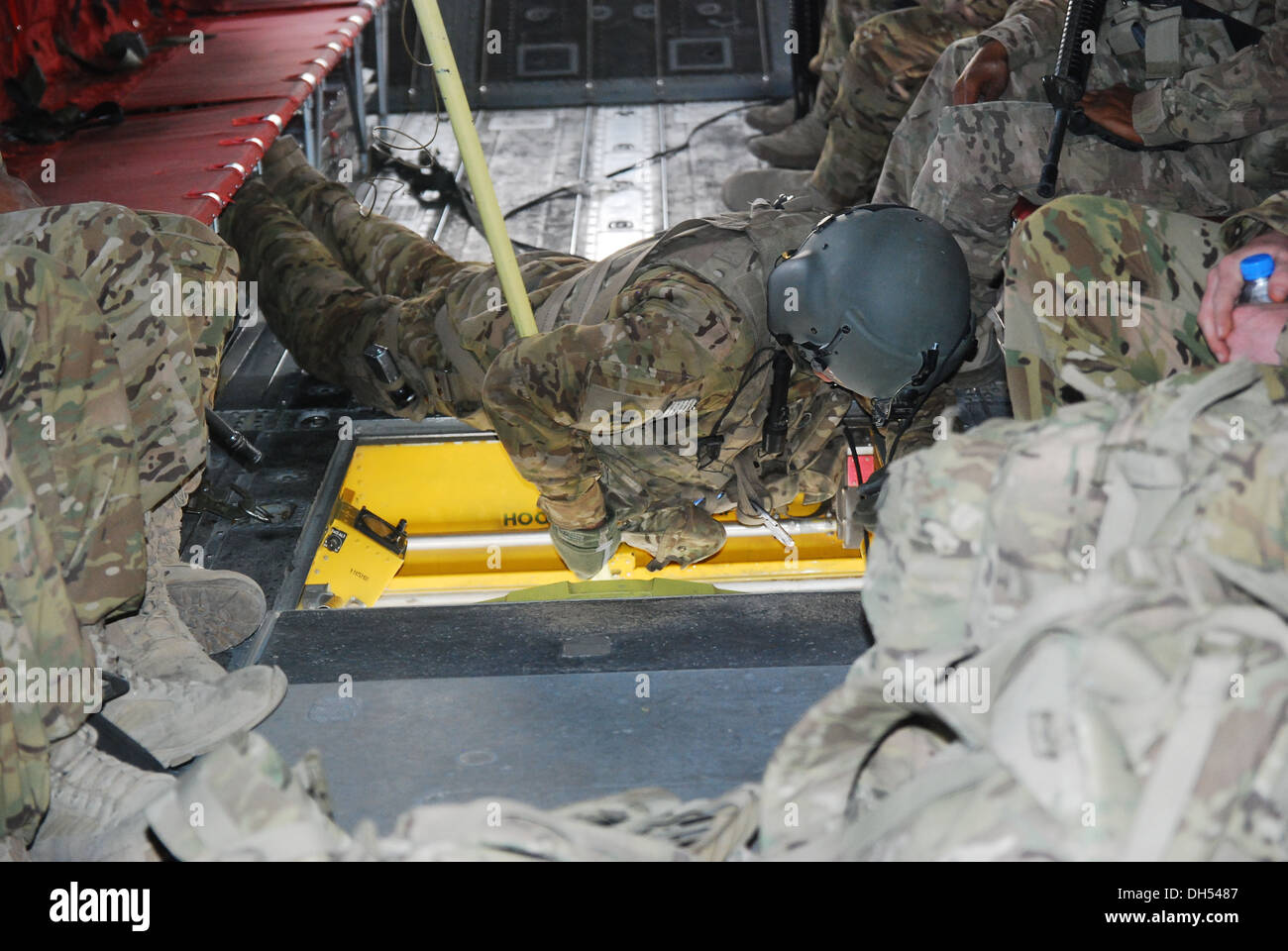 PFC. Zach Fike, ein CH-47 Chinook Hubschrauber Crewchief von Texas National Guard im Rahmen der 10. Combat Aviation Brigade, verwendet ein Sheppard Haken zur Sicherung der Takelage verwendet, um eine Schlinge Last unter den Bauch des Flugzeugs während einer Schlinge legen Stockfoto