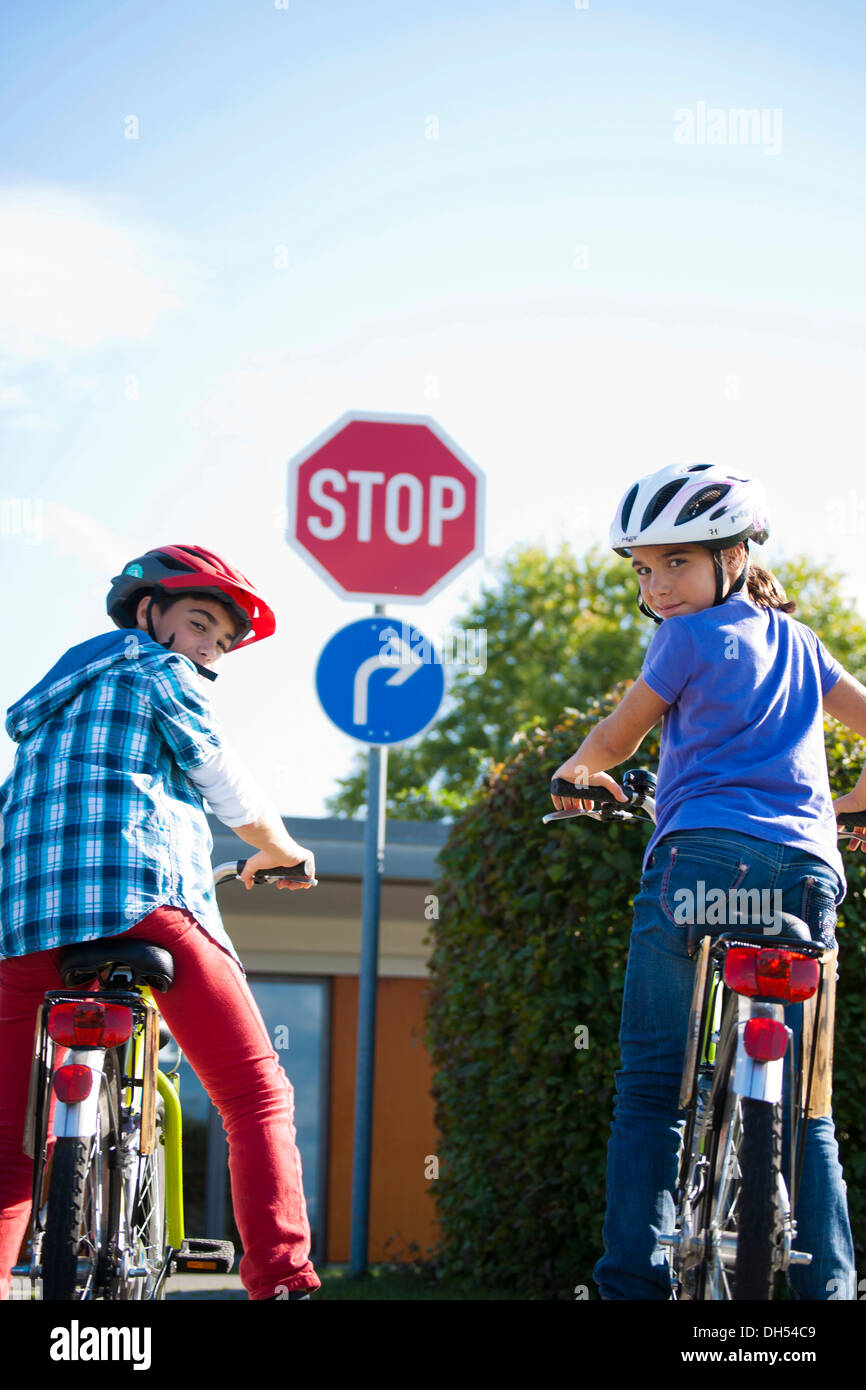 Jungen und Mädchen warten mit ihren Fahrrädern vor ein Stop-Schild Stockfoto