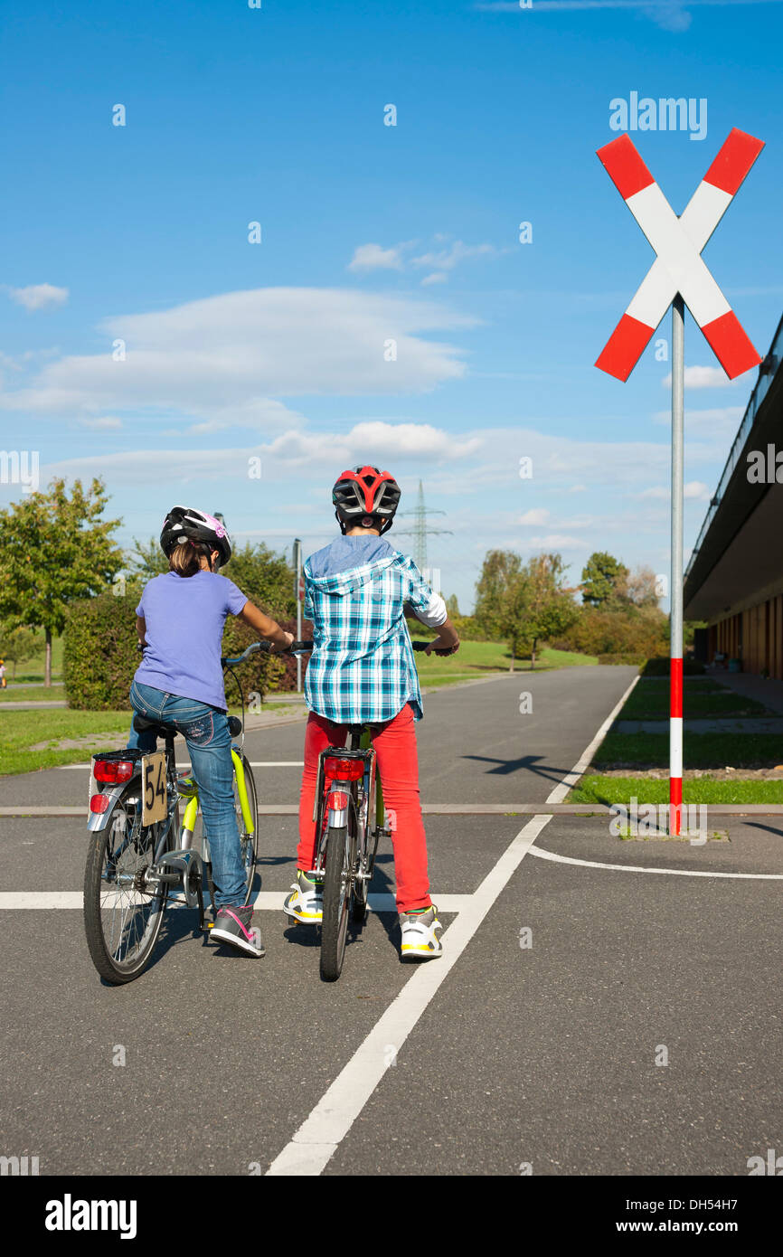 Kinder warten mit ihren Fahrrädern vor einem Bahnübergang bei einem Verkehrs-Bewusstsein-Kurs Stockfoto