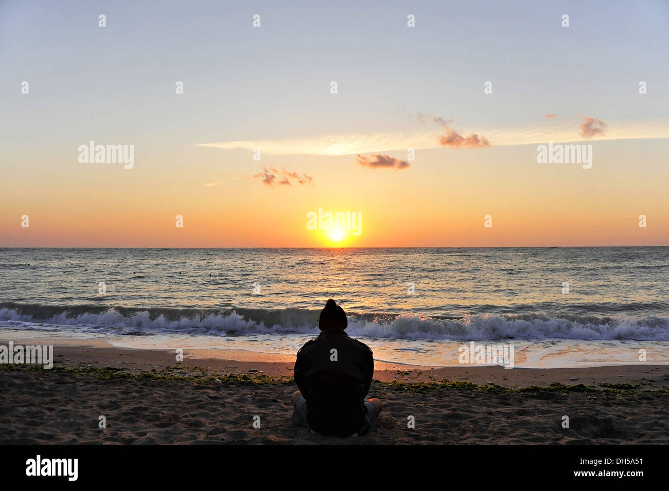 Ein Mann betrachtet den Sonnenaufgang am Meer Stockfoto