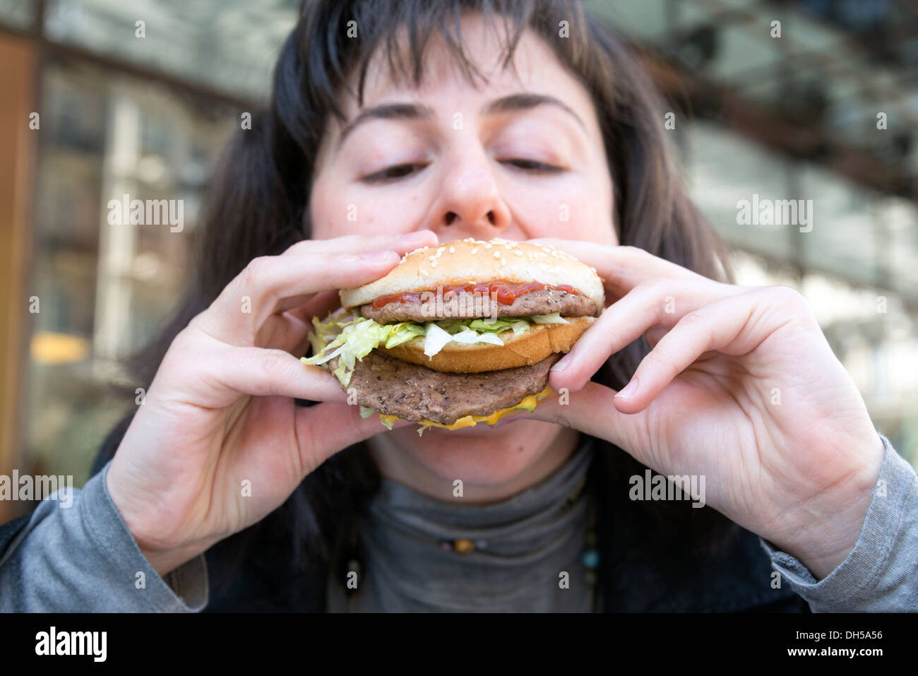 Junge Frau, die ein McDonlad Big Mac Essen Stockfoto