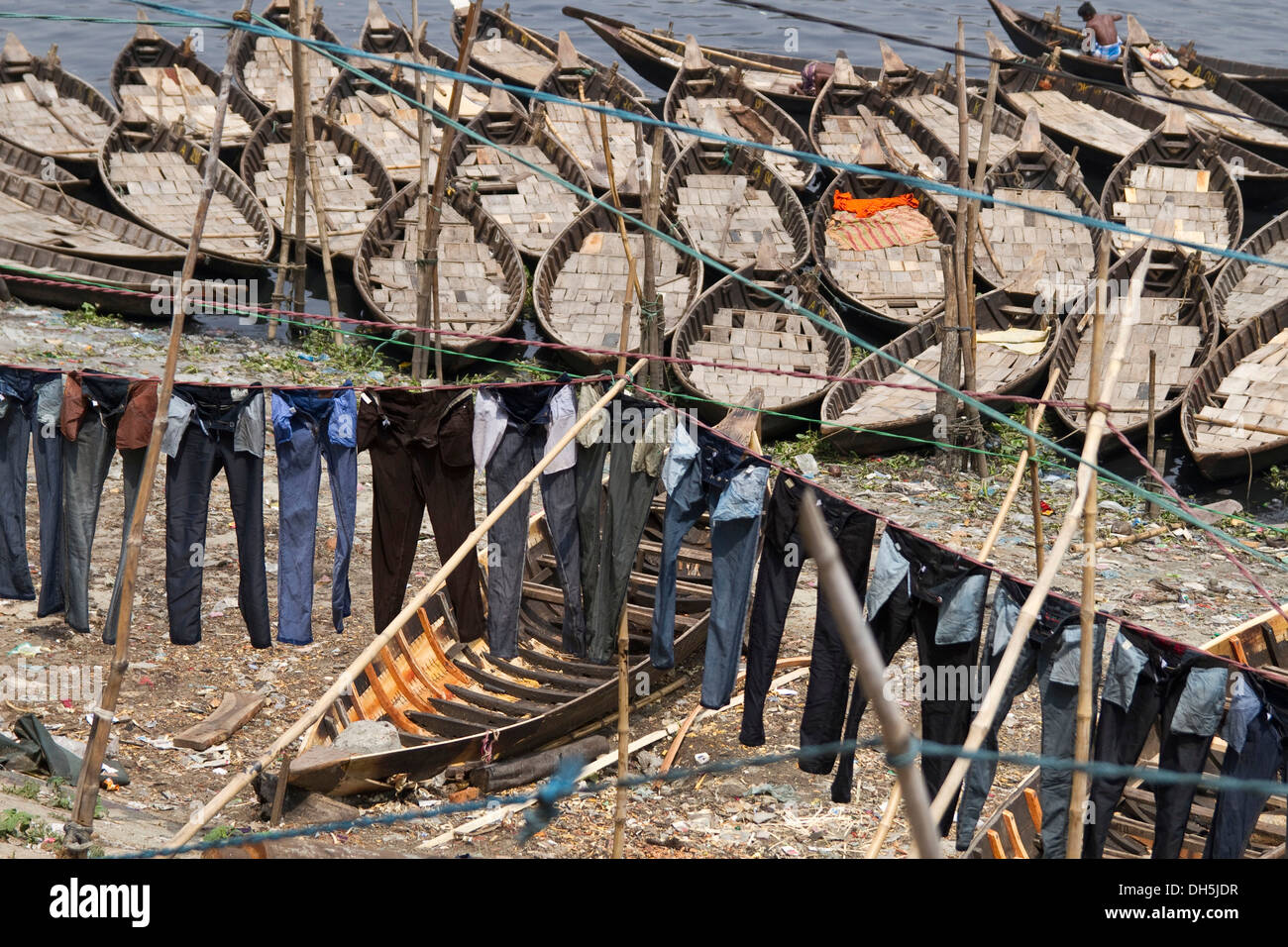 Jeans hängen zum Trocknen an Wäscheleinen vor Boote am Ufer des Flusses Buriganga, Dhaka, Bangladesch, Südasien, Asien Stockfoto