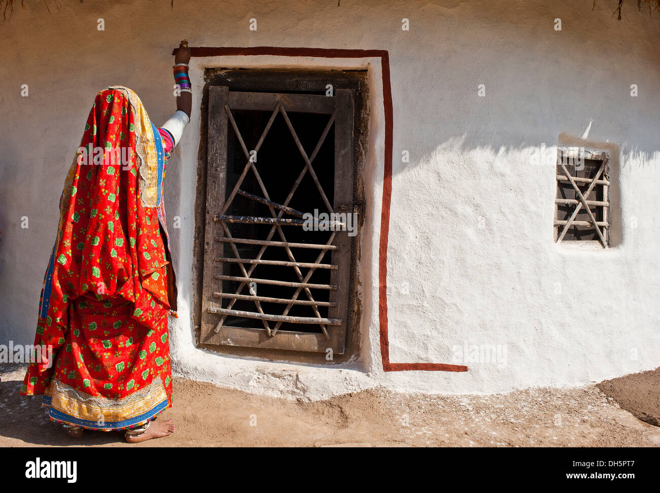 Junge indische Frau trägt einen traditionellen Sari oder Saree, malt ihre Haustür, Rajasthan, Indien, Asien Stockfoto