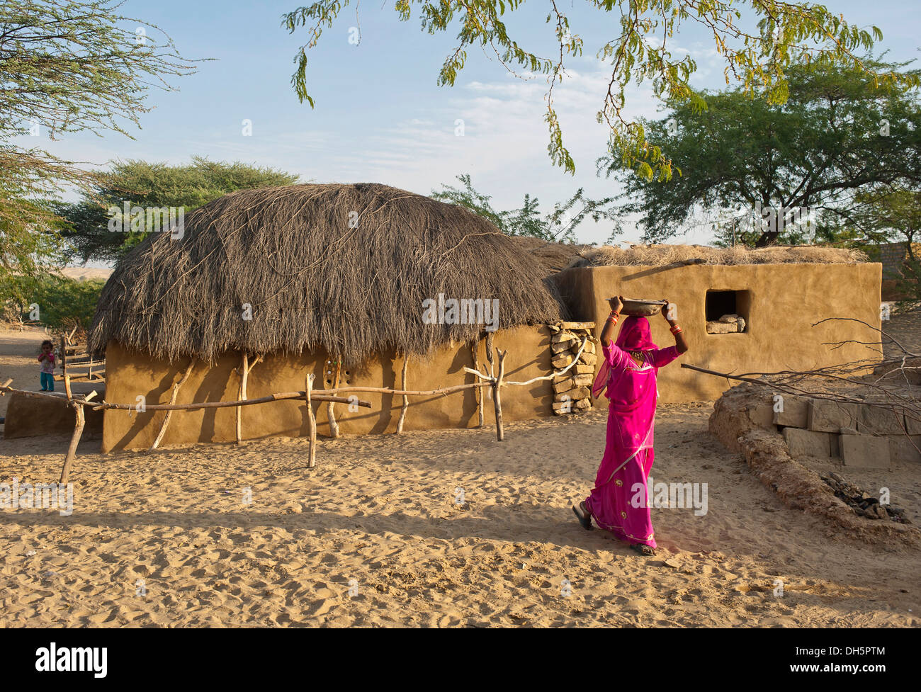Eine indische Frau trägt einen traditionellen Sari und einen Schleier über das Gesicht trägt eine Schüssel auf dem Kopf, Dorf in der Wüste Thar Stockfoto
