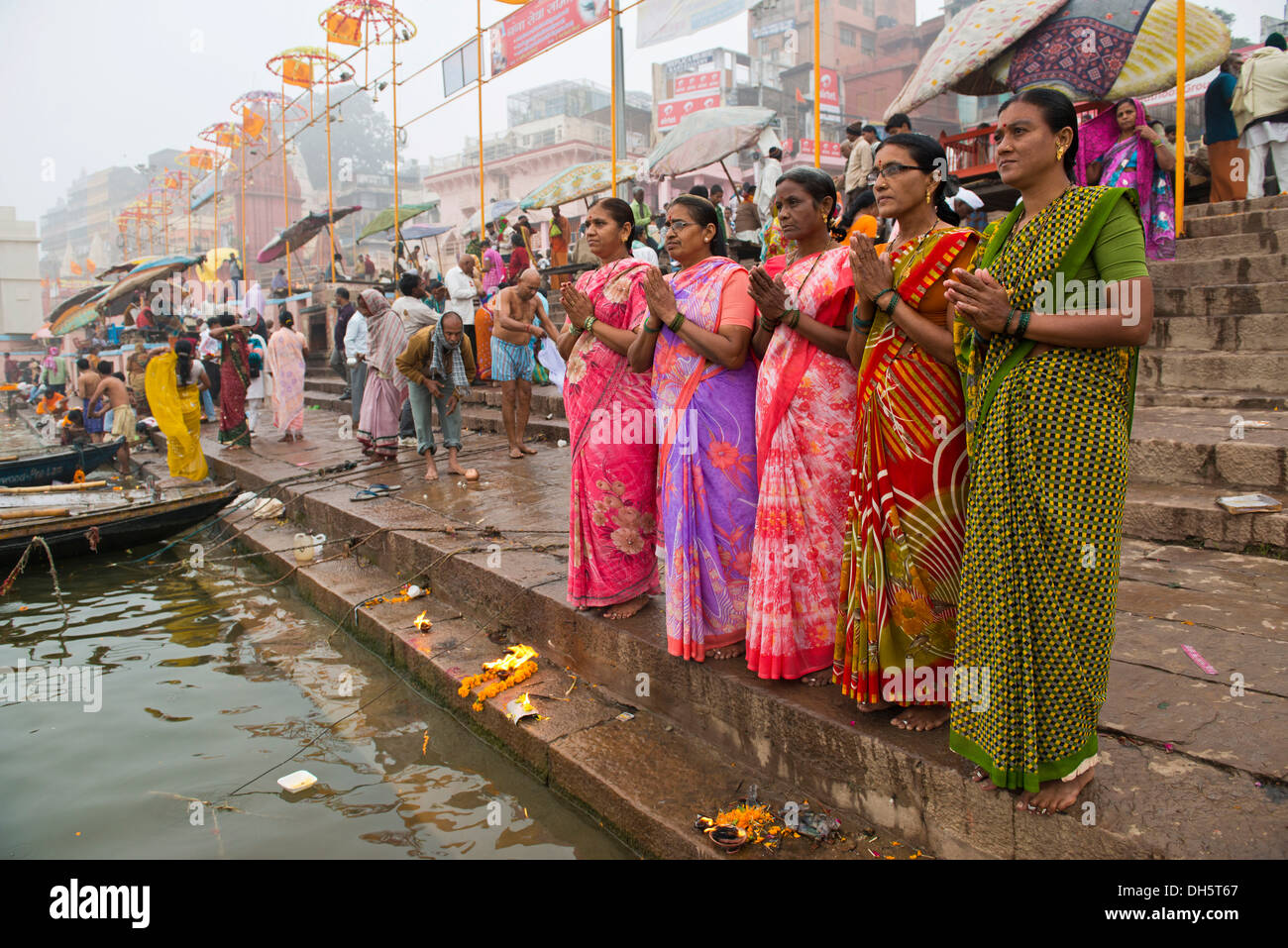 Fünf Frauen in bunten Saris im Gebet, an den Ufern des Ganges Fluß, Varanasi, Uttar Pradesh, Indien Stockfoto