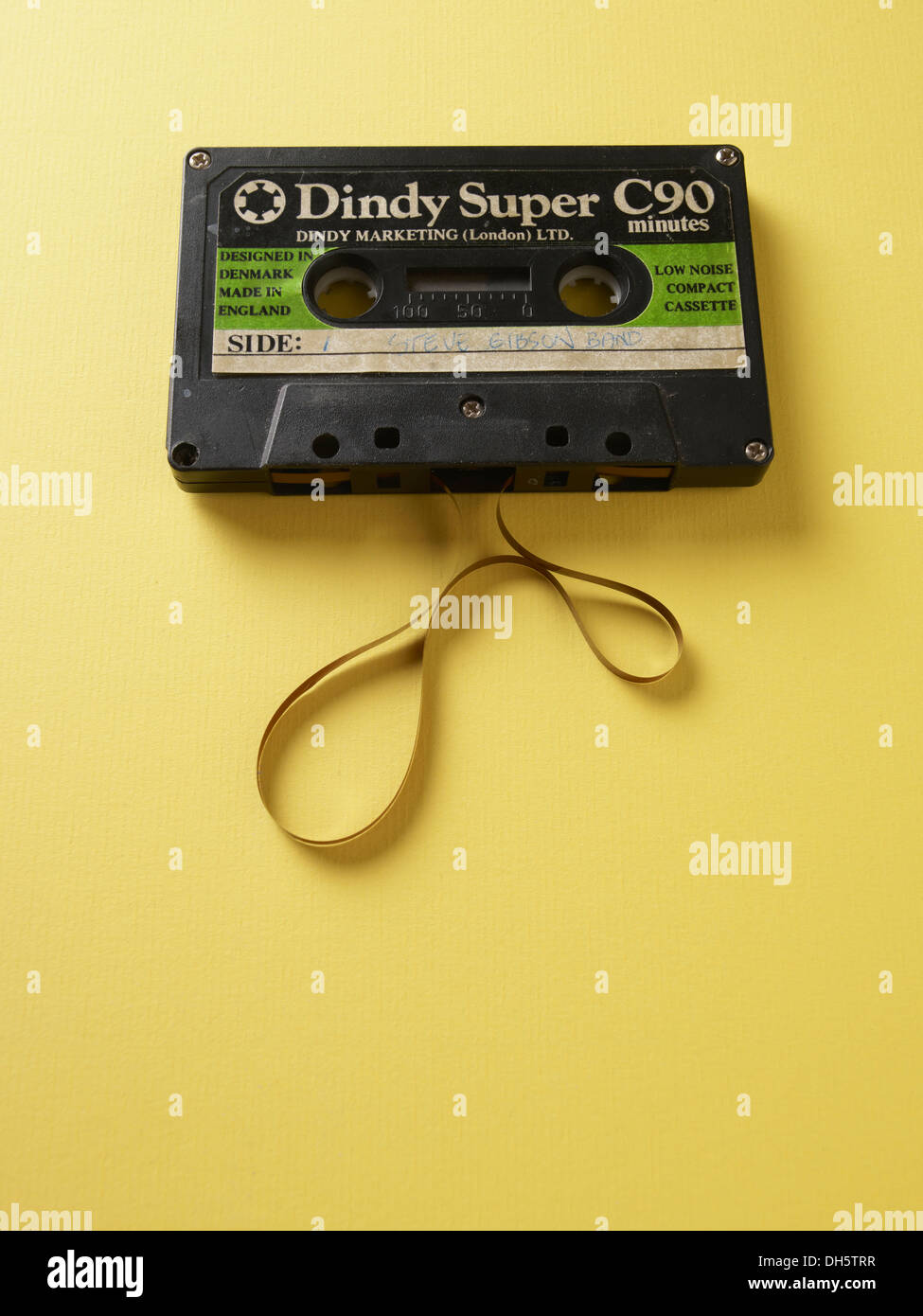 Super Dindy Audio-Kassette, bei der das Band auf einem weißen Tisch ausläuft und lockige, unordentliche Muster bildet Stockfoto