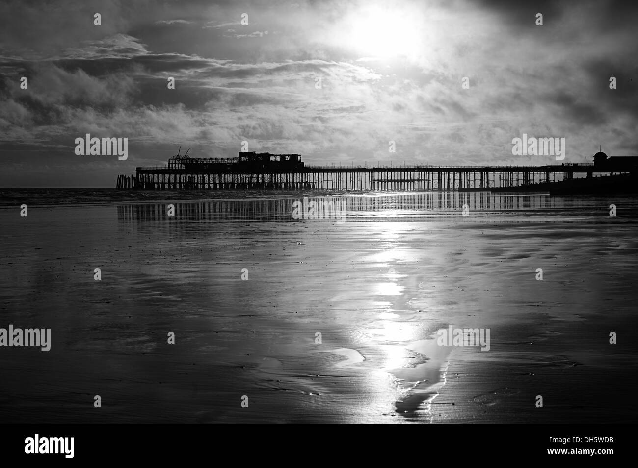 Schwarz / weiß Bild von Hastings Pier mit tiefstehende Sonne und Reflexionen, wenn Ebbe ist. Stockfoto