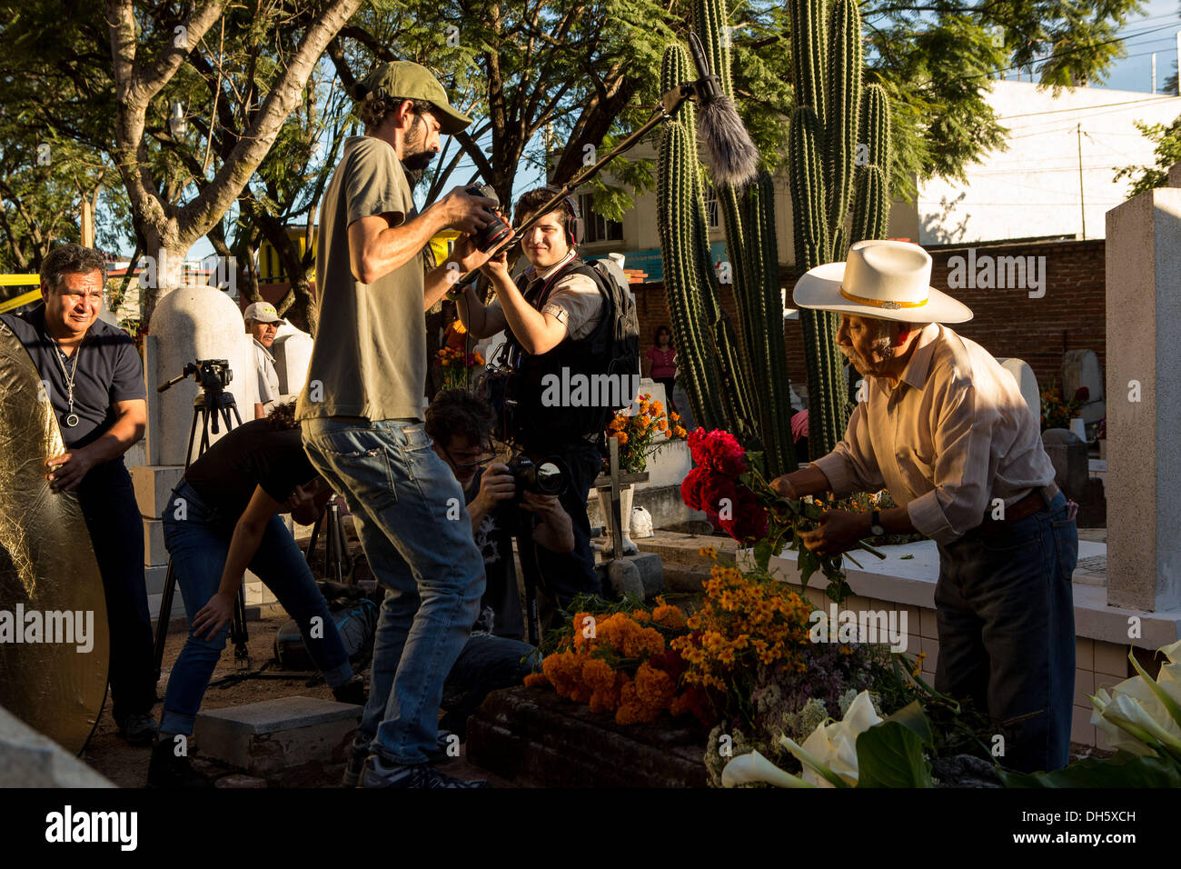 Ein Kamerateam überwältigt einen älteren Mann legen Blumen auf das Grab seiner Frau während des Tages der Toten Festival bekannt in Spanisch als D'a de Muertos auf dem alten Friedhof 31. Oktober 2013 in Xoxocotlan, Mexiko. Stockfoto