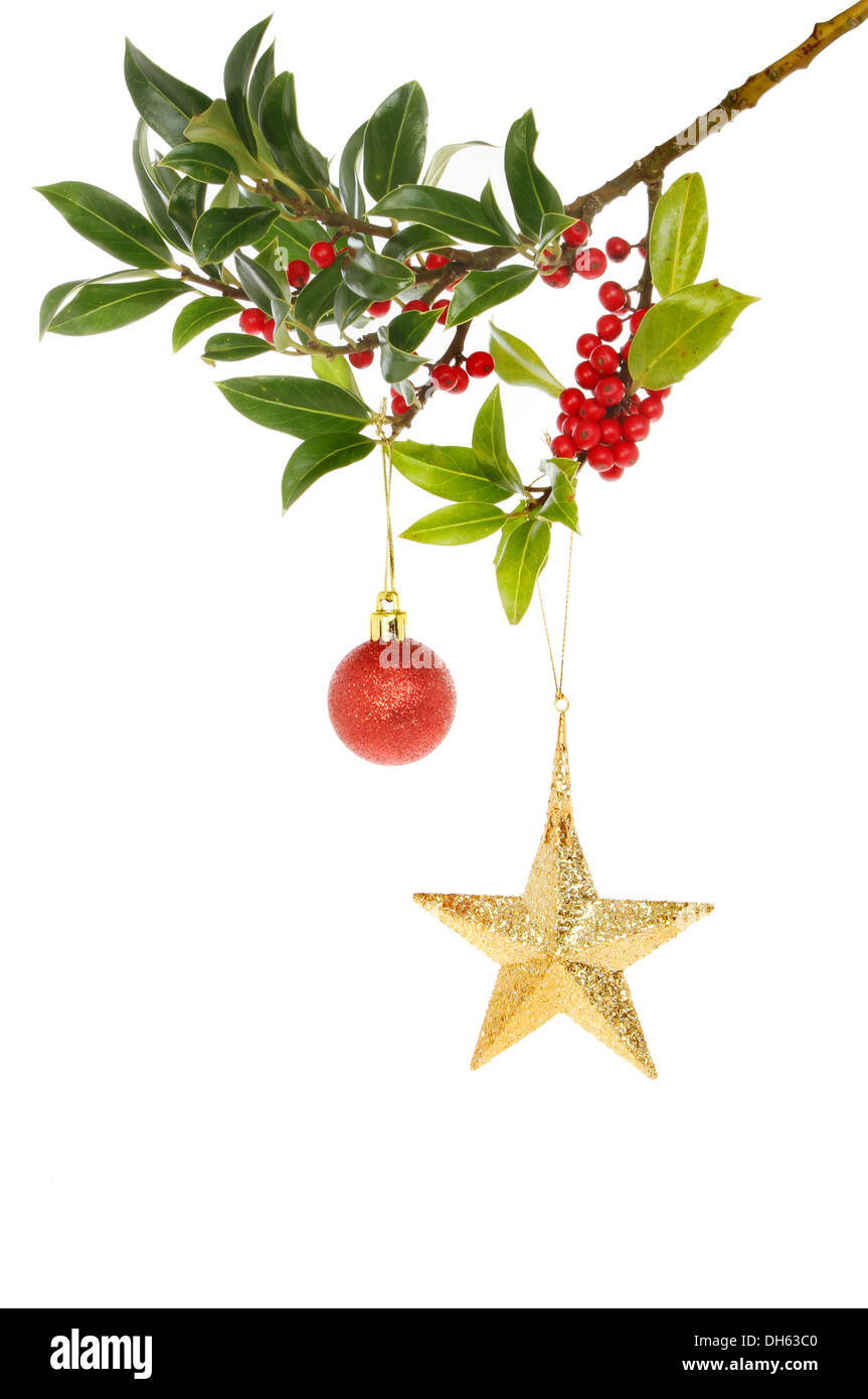 Eine Beere beladenen Holly Ast dekoriert mit einem Weihnachtsstern und Tand Stockfoto