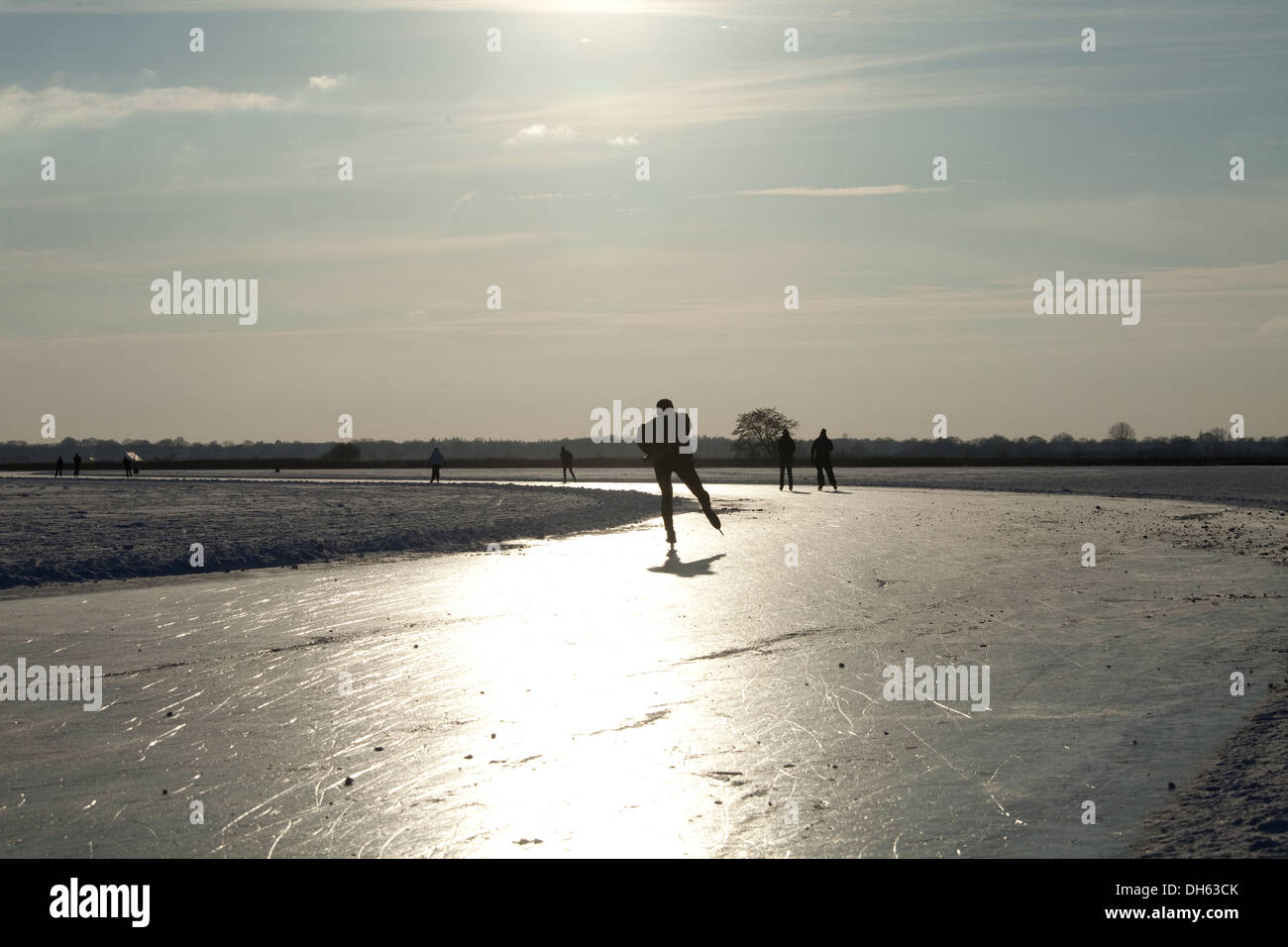 Eisläufer auf einem zugefrorenen See bei Sonnenuntergang Stockfoto