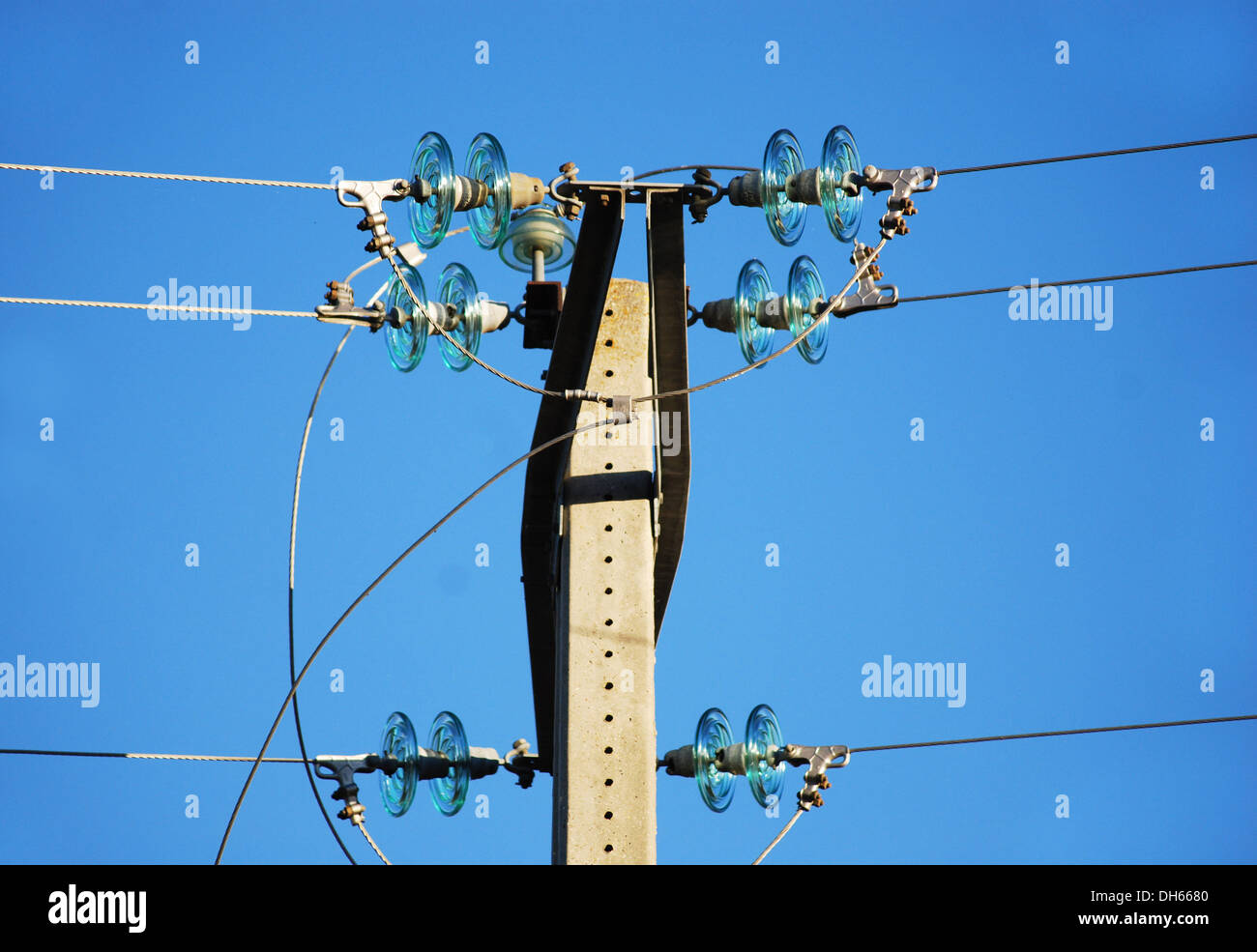 Mittelspannungs-Metall-Turm mit grünem Glas Isolatoren Hintergrundbeleuchtung auf blauen Himmel Stockfoto