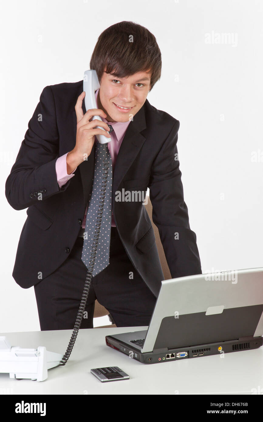 Junger Mann stehend auf einem Laptop und hält eine Telefon Stockfoto