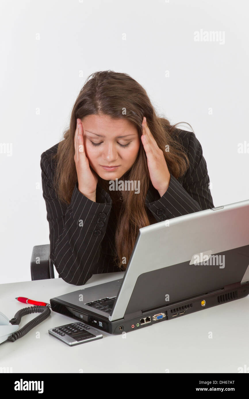 Junge Frau an ihrem Schreibtisch mit einem Laptop-Computer, Kopfschmerzen Stockfoto