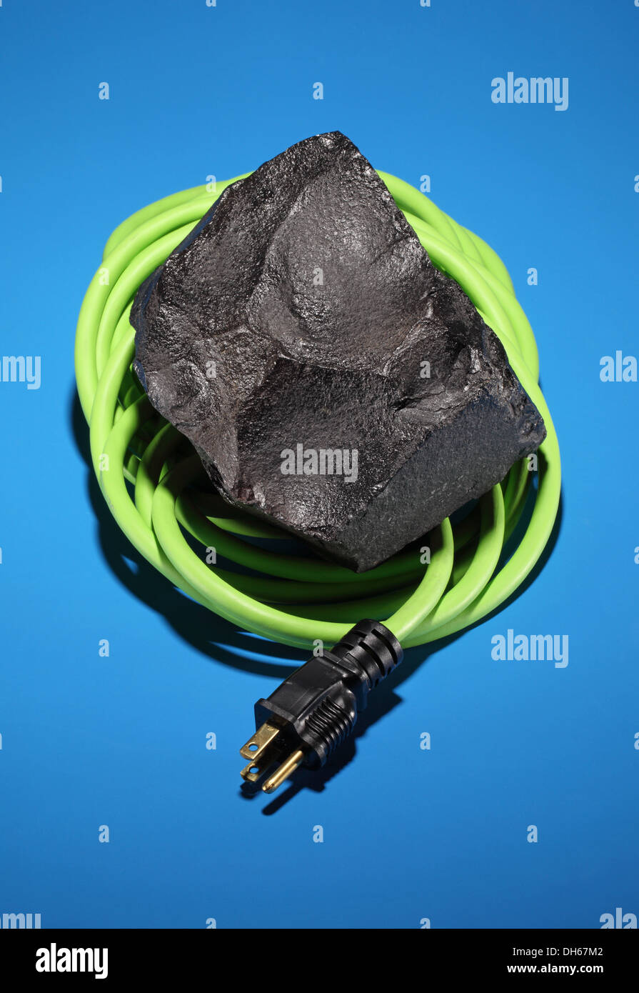Ein schwarzes Stück Kohle gewickelt mit einem grünen elektrischen Kabel und Stecker Stockfoto