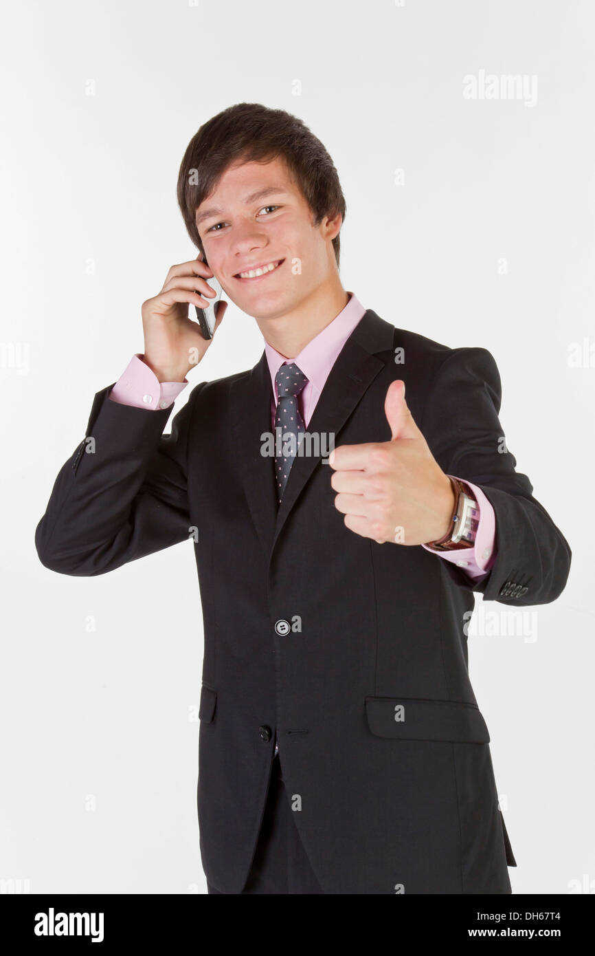 Junger Mann mit einem Anzug und Krawatte mit einem Mobiltelefon geben einen Daumen nach oben Stockfoto