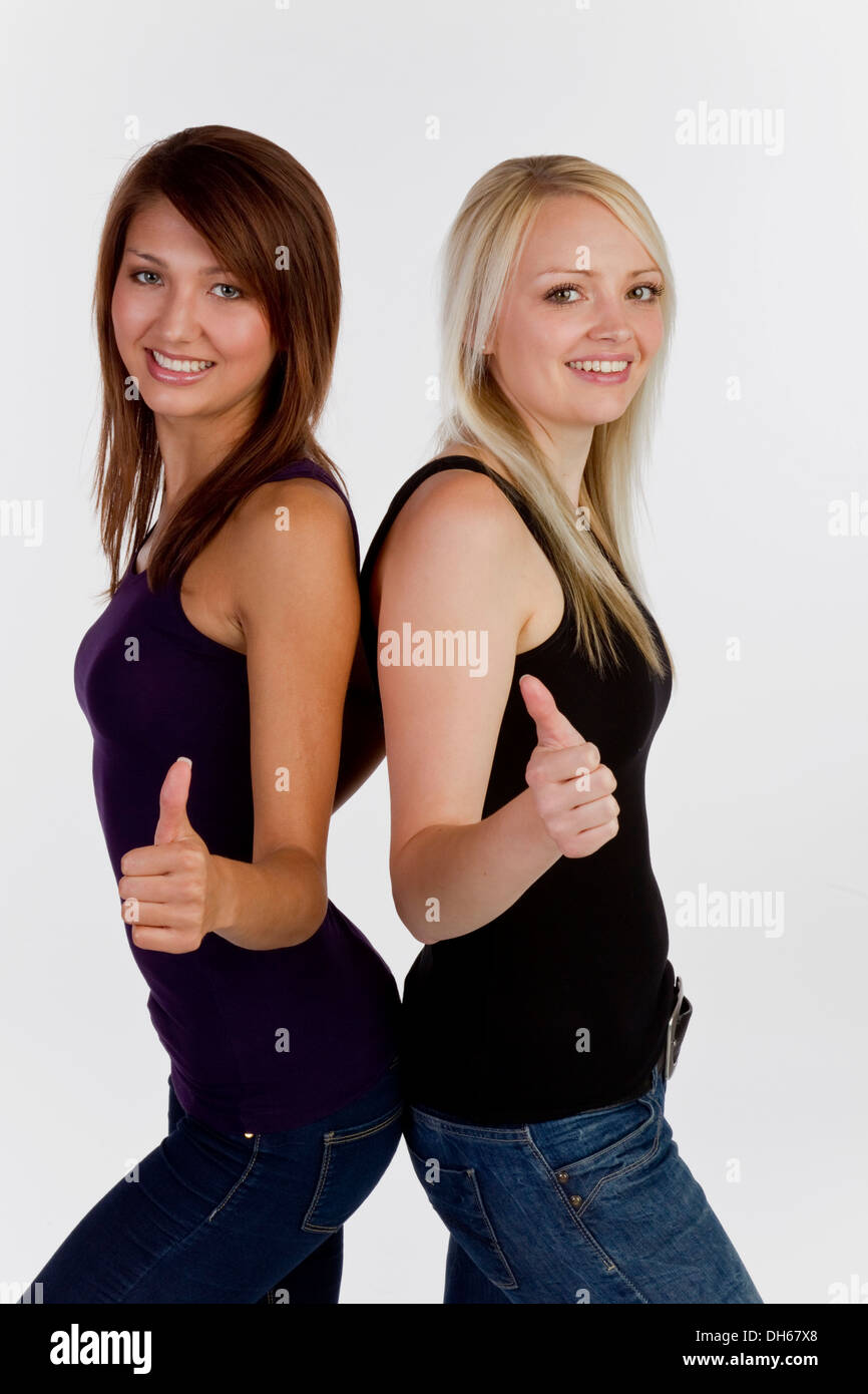 Zwei junge Frauen Blick in die Kamera macht Daumen hoch Geste lächelnd Stockfoto