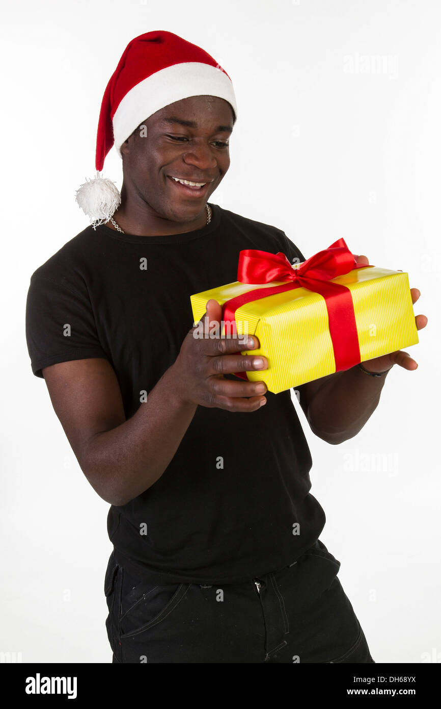 Junger schwarzer Mann trägt eine Weihnachtsmütze und hält ein Geschenk Stockfoto