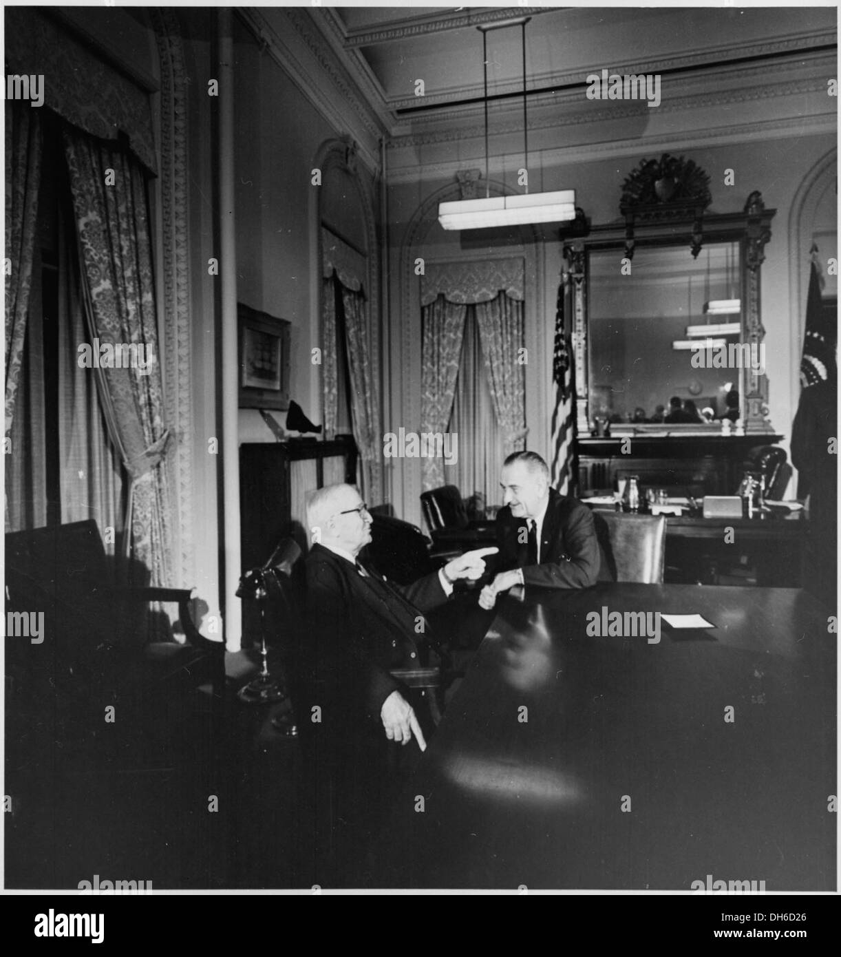 Dieses Foto zeigt den ehemaligen Präsidenten Harry S. Truman im Gespräch mit Präsident Lyndon B. Johnson, der wahrscheinlich im Weißen Haus während einer politischen Diskussion oder eines Treffens zwischen den beiden Führern aufgenommen wurde. Stockfoto