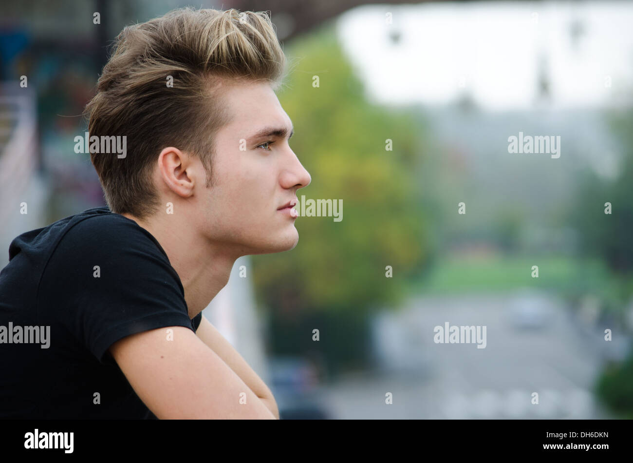 Profil von Schuss attraktive blonde jungen Mannes in der Stadt, der Ferne im Freien suchen Stockfoto