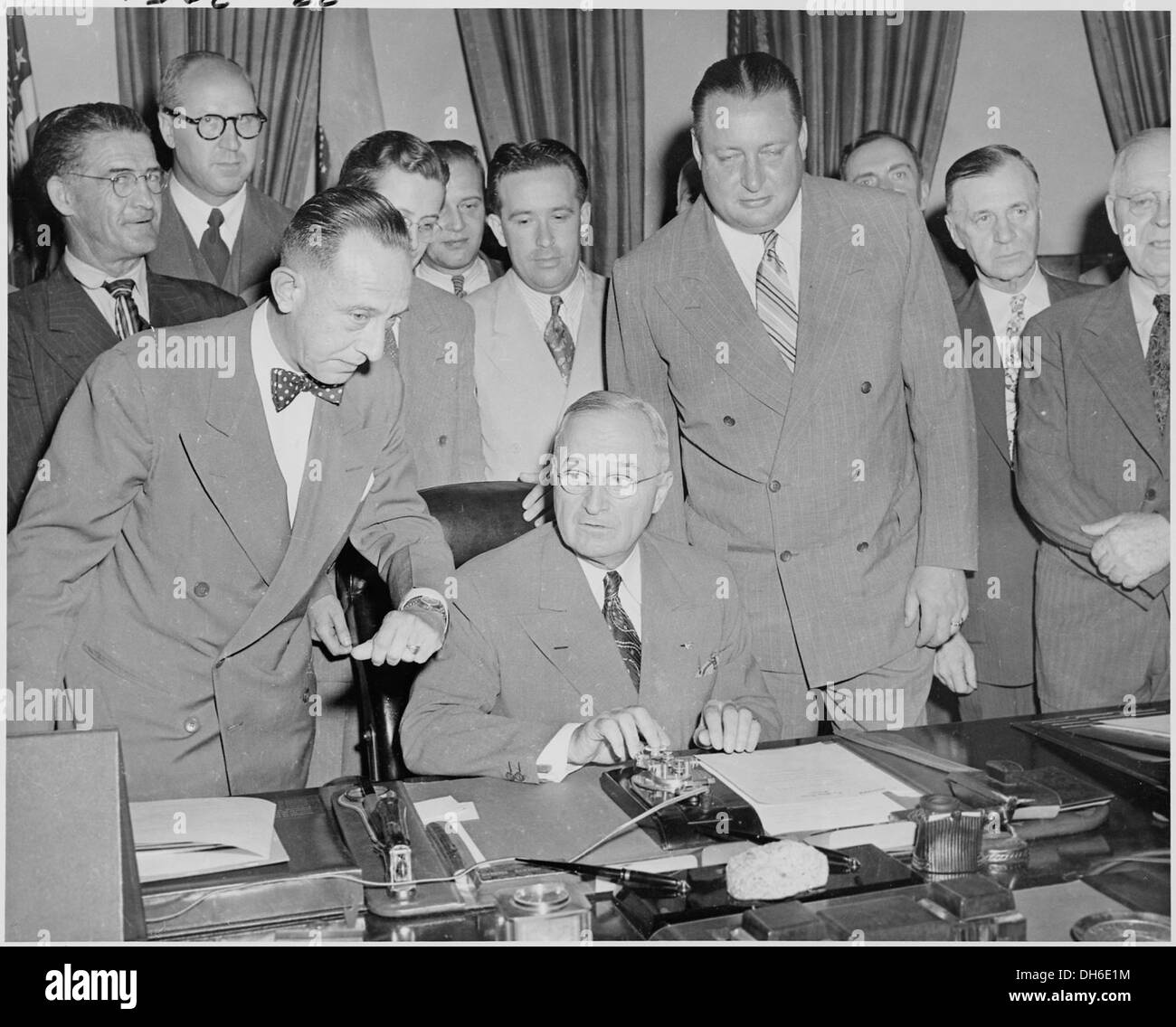 Präsident Harry S. Truman ist an seinem Schreibtisch im Oval Office abgebildet, der sich darauf vorbereitet, einen neuen Generator zu aktivieren. Dieses Bild zeigt einen Moment der präsidialen Entscheidungsfindung im Herzen der Operationen der US-Regierung. Stockfoto