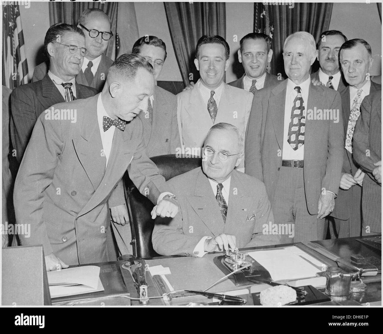 Präsident Harry S. Truman ist an seinem Schreibtisch im Oval Office abgebildet, der sich darauf vorbereitet, einen neuen Generator zu aktivieren. Das Foto spiegelt Trumans Beteiligung an technologischen Fortschritten während seiner Präsidentschaft wider, einer Zeit bedeutender politischer und militärischer Veränderungen in den USA Stockfoto