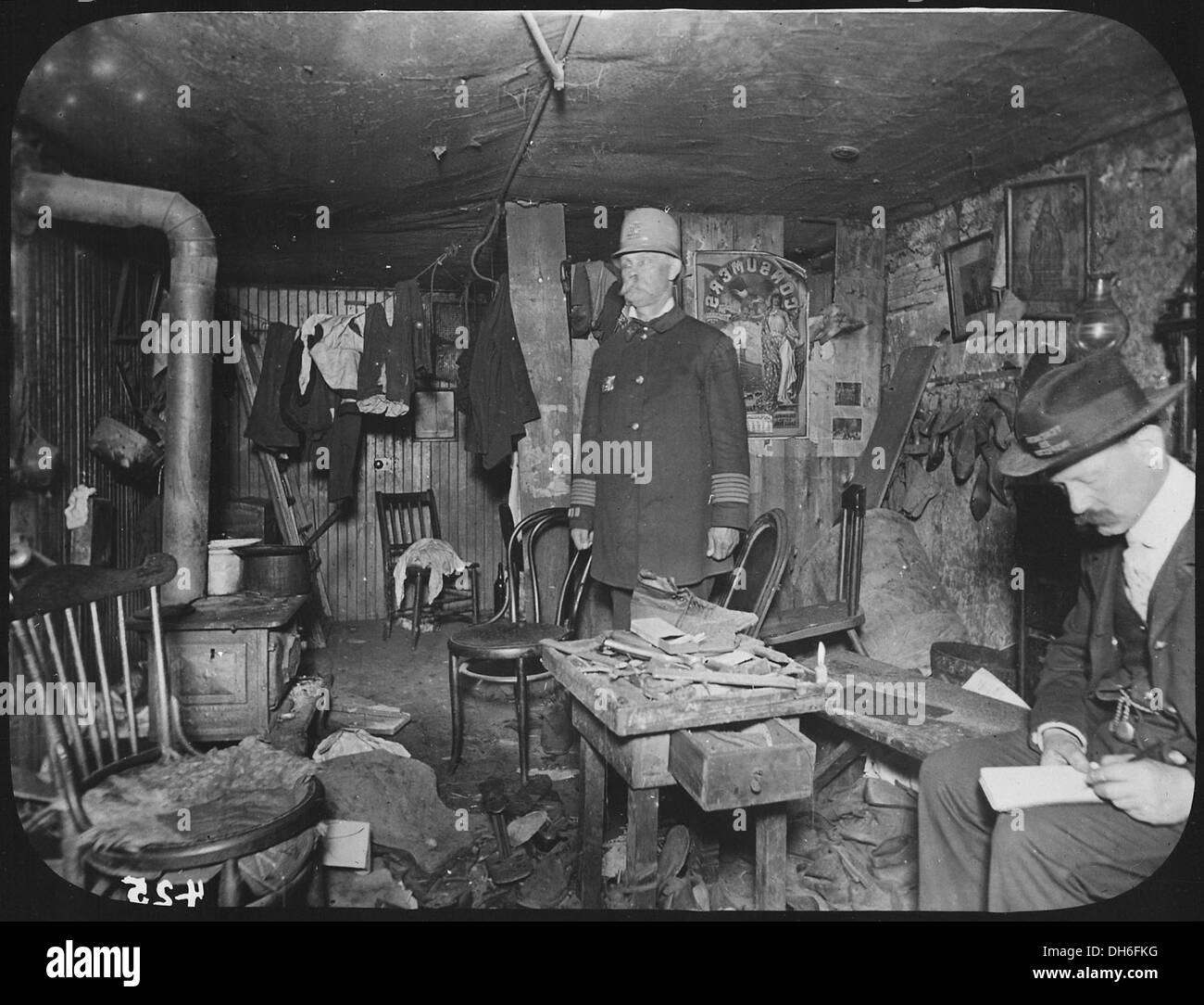 Zwei Beamte der New York City Tenement House Abteilung untersuchen einen unaufgeräumten Keller Wohnzimmer, ca. 1900 535469 Stockfoto