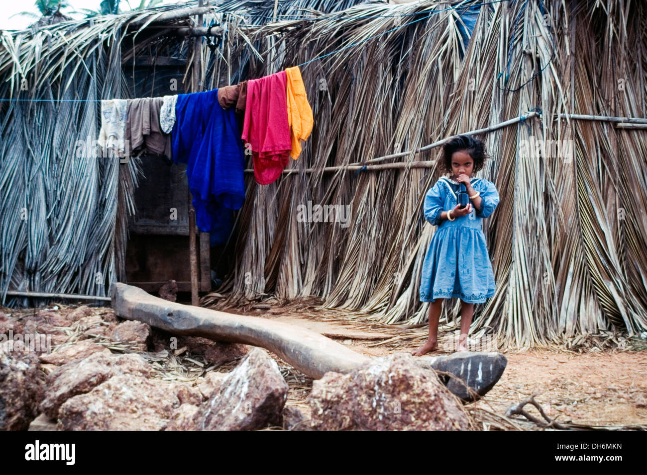 junge Mädchen trinken aus der Flasche vor ihrer Familie Stroh gebaut Hause Benaulim Goa Indien Stockfoto