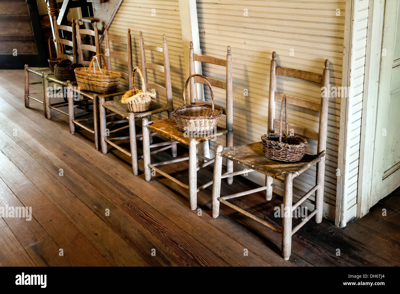 Zeile der Leiter zurück Holzstühle in der Eingangshalle eines alten Bauernhauses der Cracker mit geflochtenen Körben Holz. Newberry, Florida USA Stockfoto