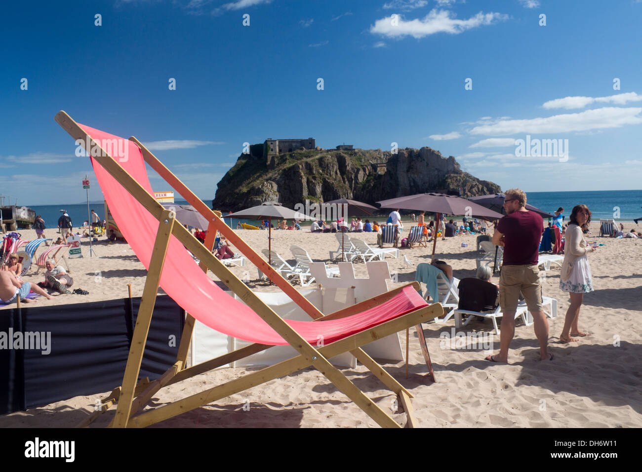 Riesige Liegestuhl auf Schloss Strand Tenby Pembrokeshire Wales britische Leute am Strand im sonnigen Sommertag Stockfoto