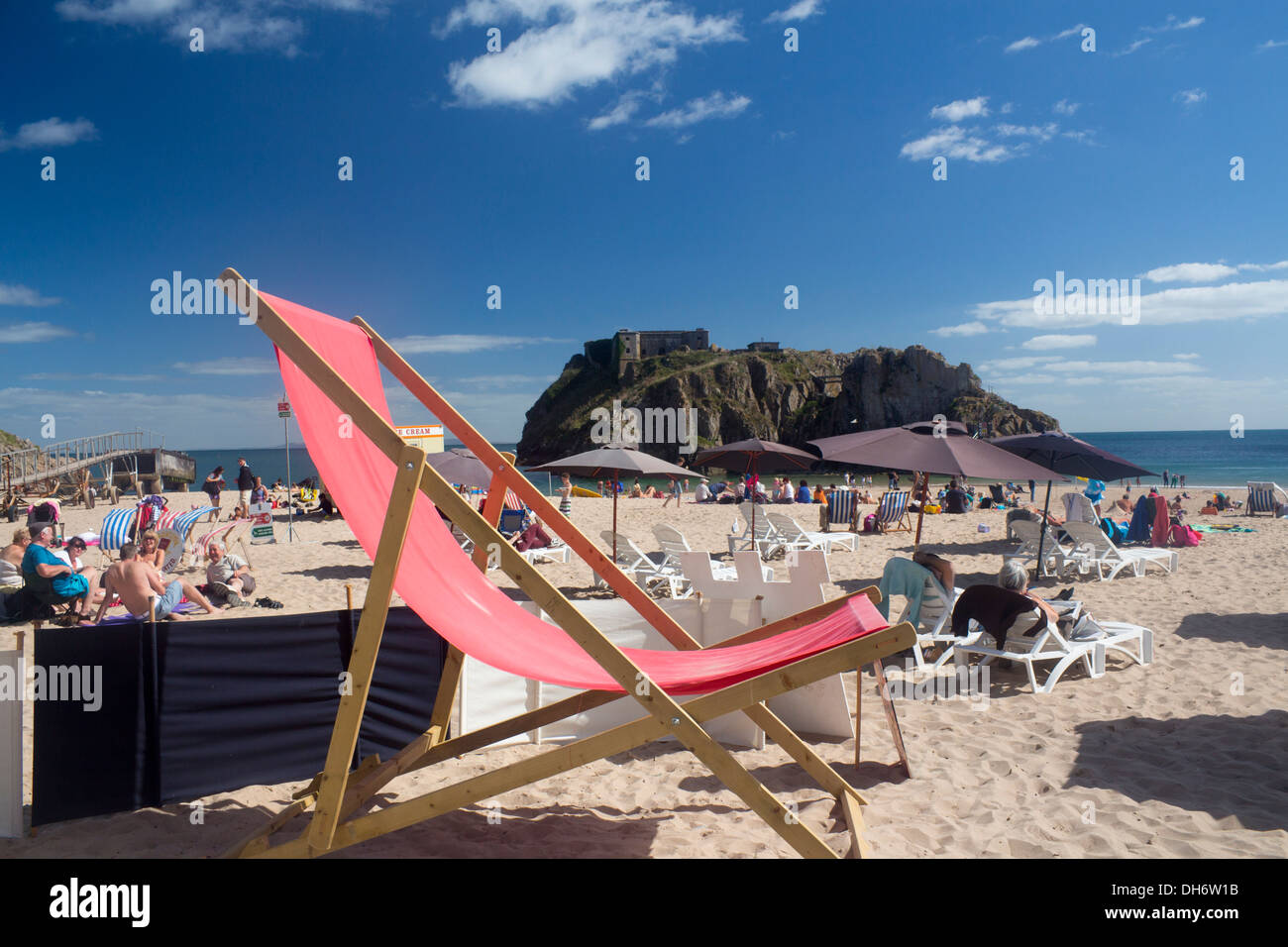 Riesige Liegestuhl auf Schloss Strand Tenby Pembrokeshire Wales britische Leute am Strand im sonnigen Sommertag Stockfoto