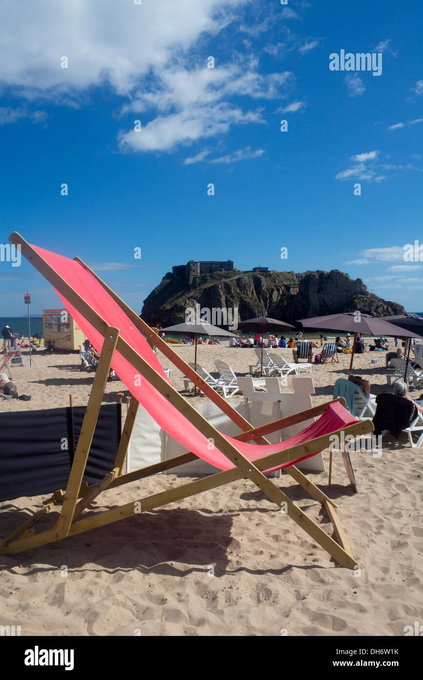 Riesige Liegestuhl auf Schloss Strand Tenby Pembrokeshire Wales britische Leute am Strand im sonnigen Sommertag Stockfoto