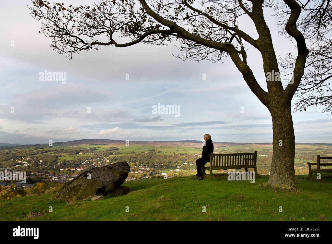 Eine Person allein Ansichten Ilkley Stadt in Yorkshire von der Spitze des Ilkley Moor. Stockfoto
