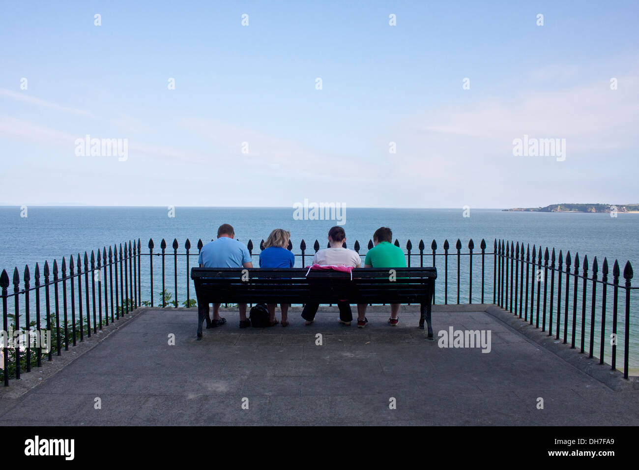 Vier Menschen saßen auf einer Bank mit Blick auf das Meer. Stockfoto