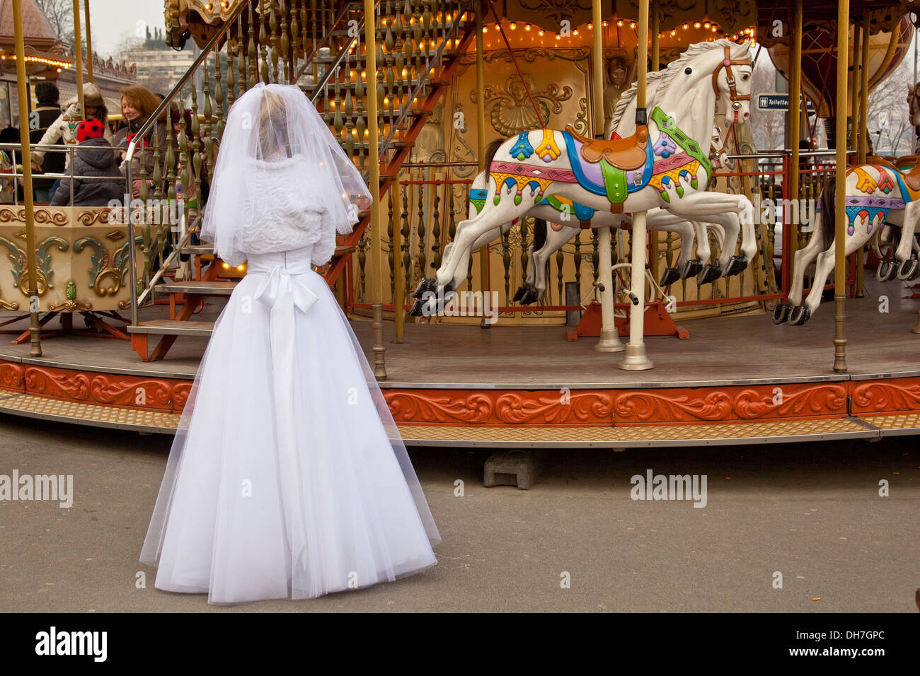Braut im Hochzeitskleid steht ein Karussell in Paris Stockfoto