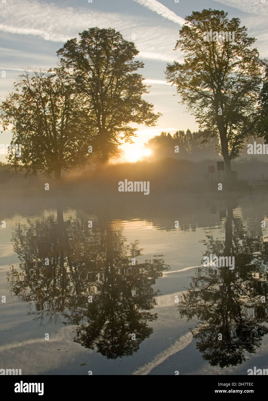 Herbstliche Flusslandschaft mit Bäumen spiegelt sich im Wasser und steigender Nebel. Stockfoto
