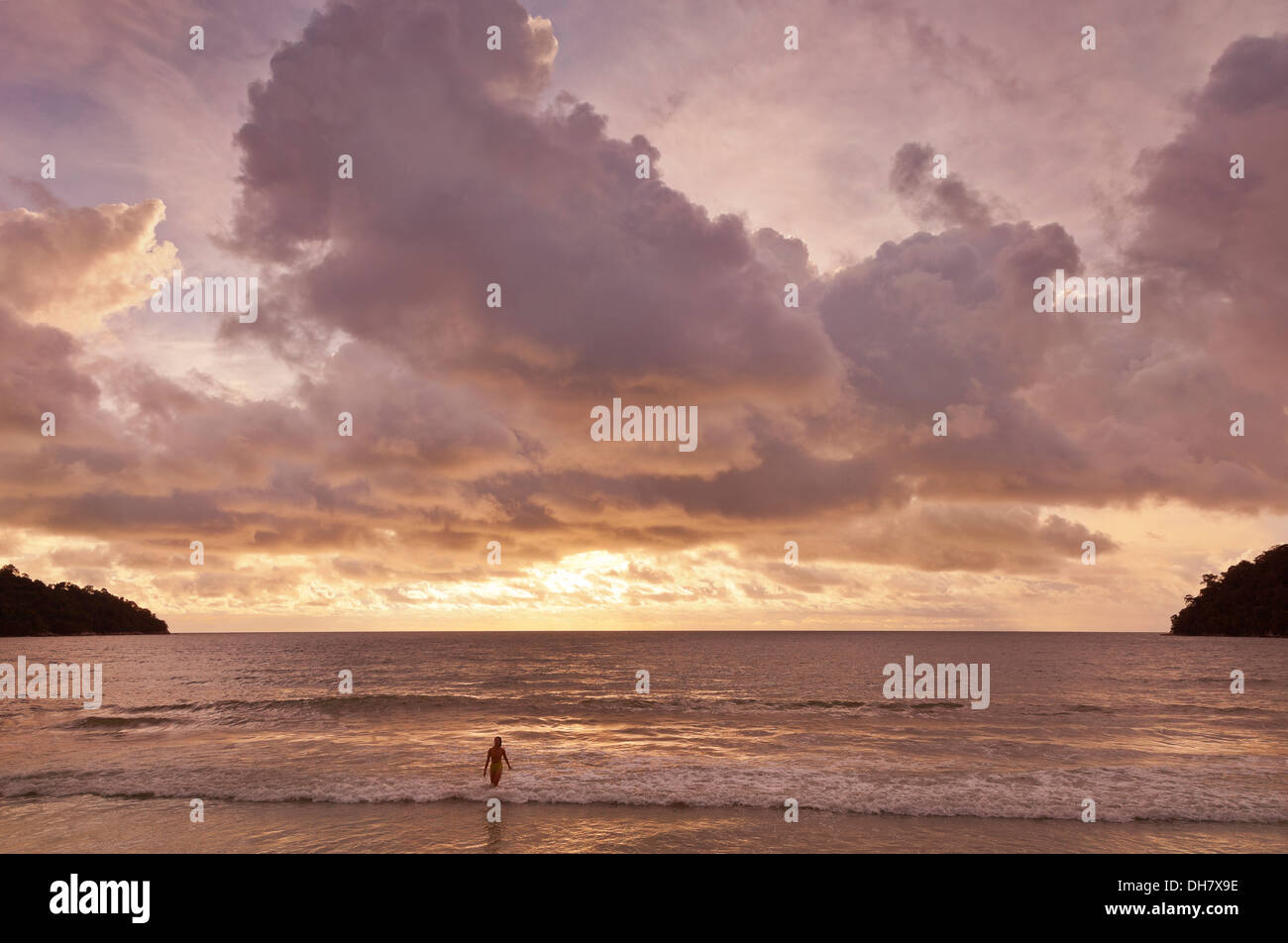 Strand Sonnenuntergang, Pulau Pangkor, Malaysia, einsame weibliche Schwimmer durchläuft die Incomong surf Stockfoto