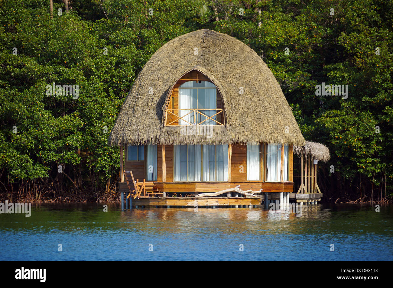 Reetgedeckten Bungalow über dem Wasser mit üppiger tropischer Vegetation im Hintergrund, Karibik, Mittelamerika, Bocas del Toro, Panama Stockfoto