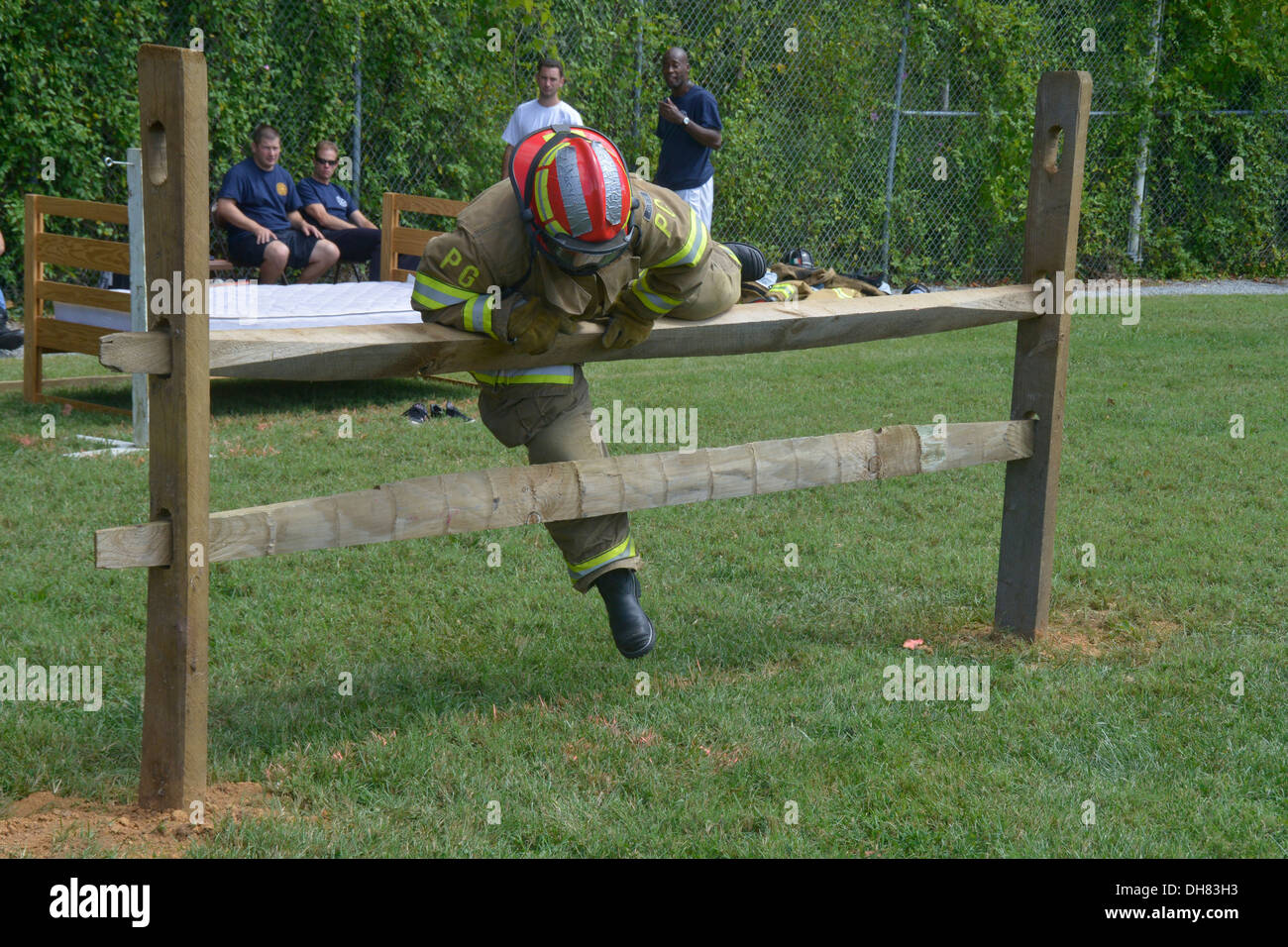 Feuerwehrmann springt eine Geländer während einer Feuerwehr-Drill, ihre Fähigkeiten zu testen Stockfoto