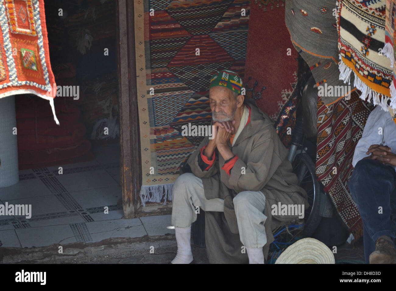Weiser alter marokkanischer Mann sitzt vor seinem Geschäft im Souk, Marrakesch Stockfoto