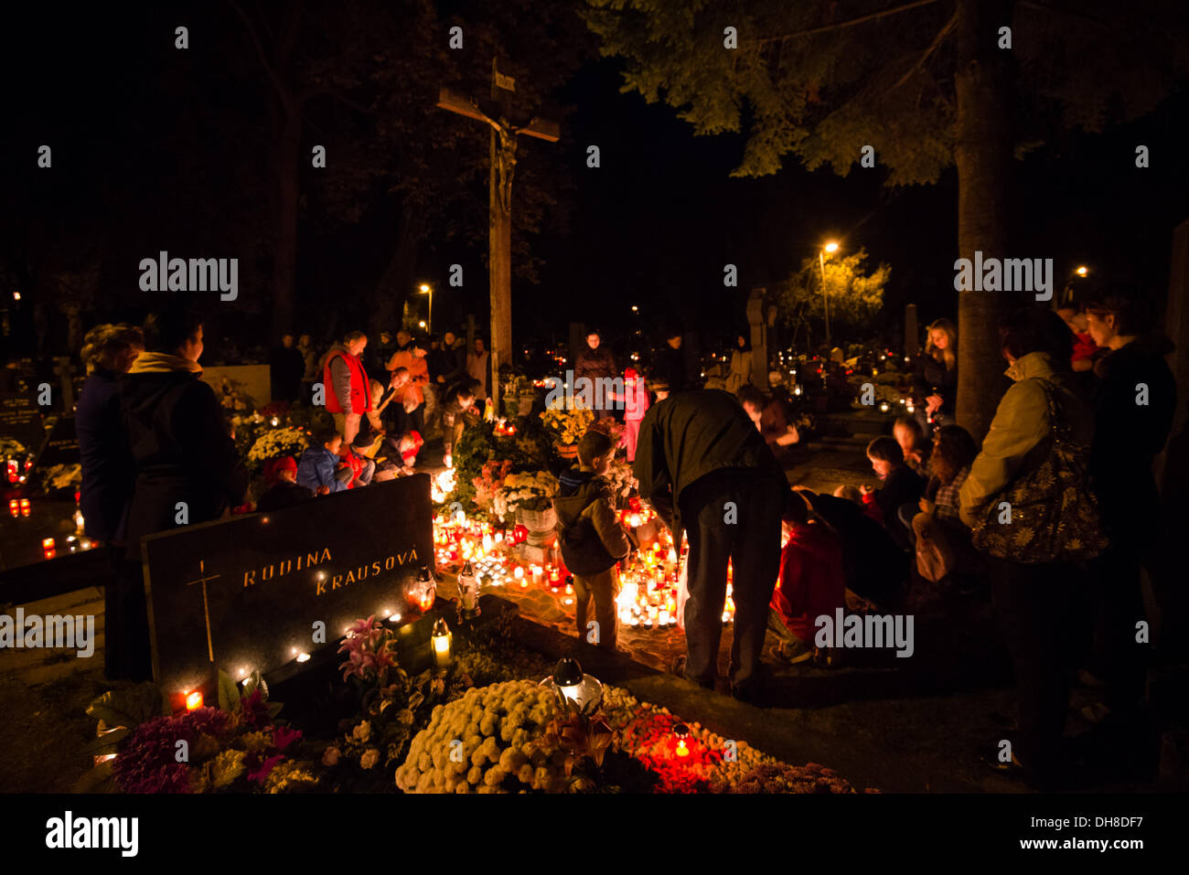 PEZINOK, Slowakei - NOVEMBER 1: Menschen stehen und beten vor Kreuz mit brennenden Kerzen am Boden während Allerheiligen am 1. November 2013. Stockfoto