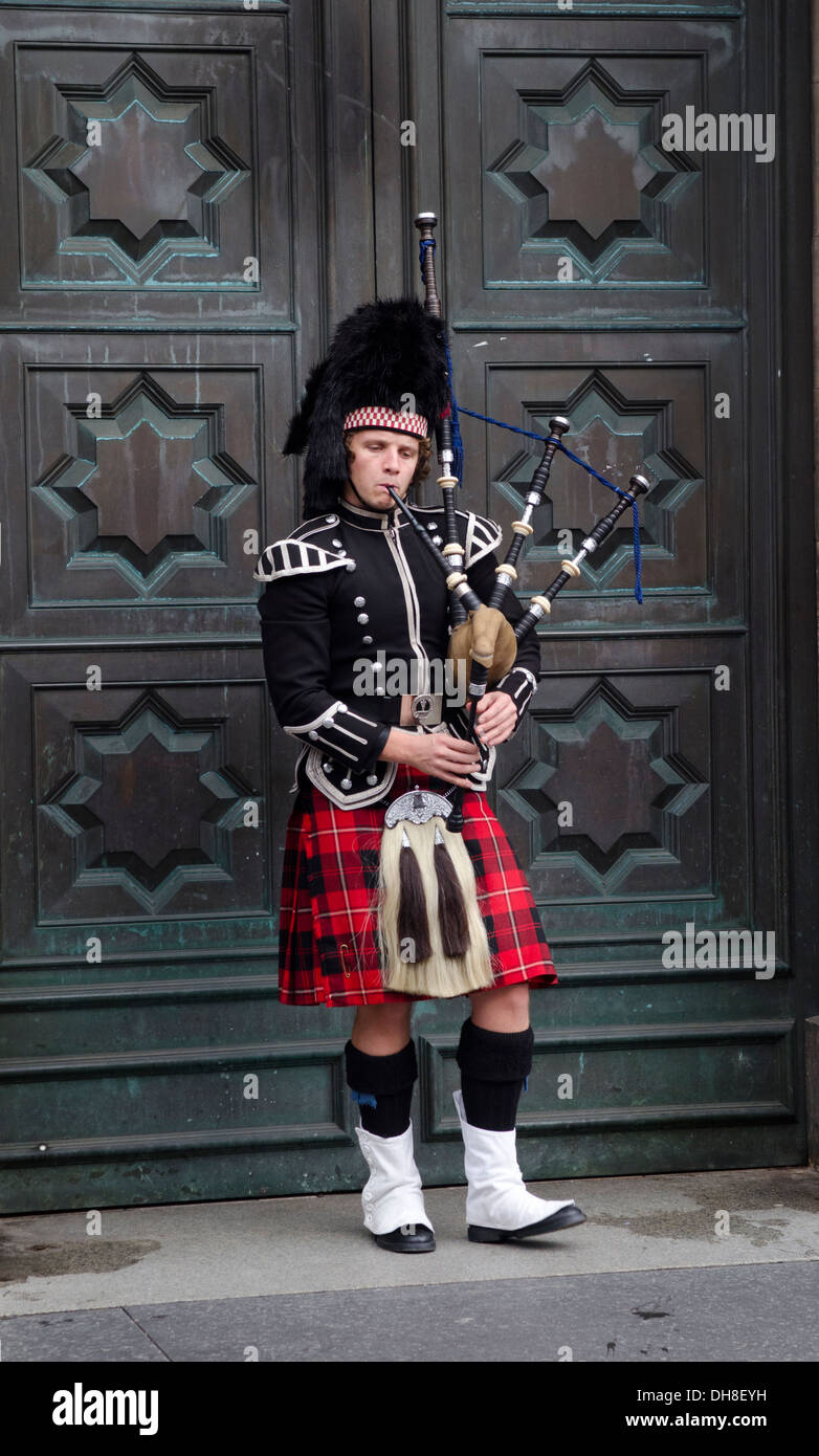 Piper in traditioneller Tracht Dudelsack vor große Tür auf der Royal Mile in Edinburgh Stockfoto